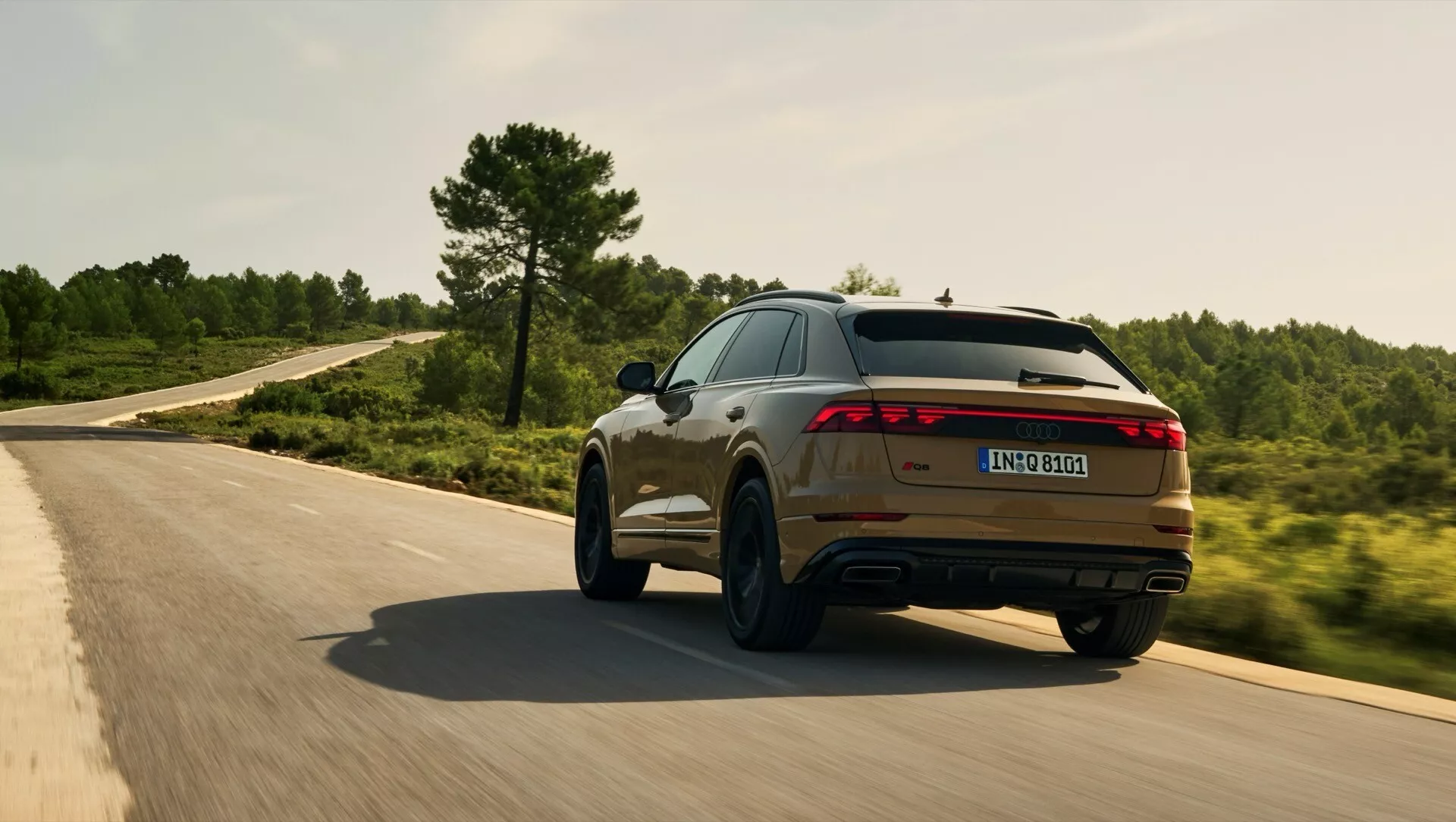 Audi Q8 2023 (4M-Facelift) v pohybe na zákrute, ukazujúce svoj športový zadný a bočný profil s LED svetelnou lištou, duálnym výfukom a metalízou
