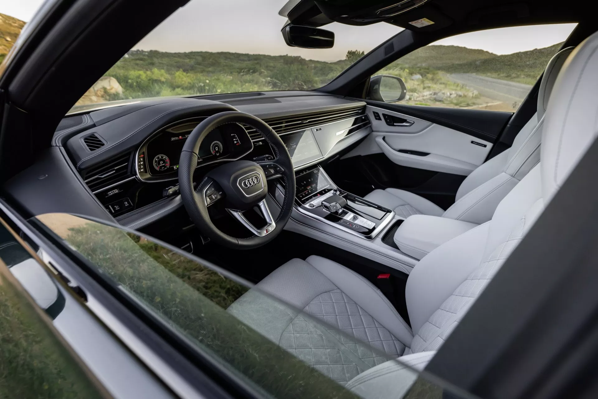 Interiérový pohľad na Audi Q8 2023 (4M-Facelift) zdôrazňujúci kokpit na strane vodiča s digitálnym prístrojovým panelom, dotykovým informačným systémom a luxusnými prvkami ako kožené čalúnenie a kovové akcenty