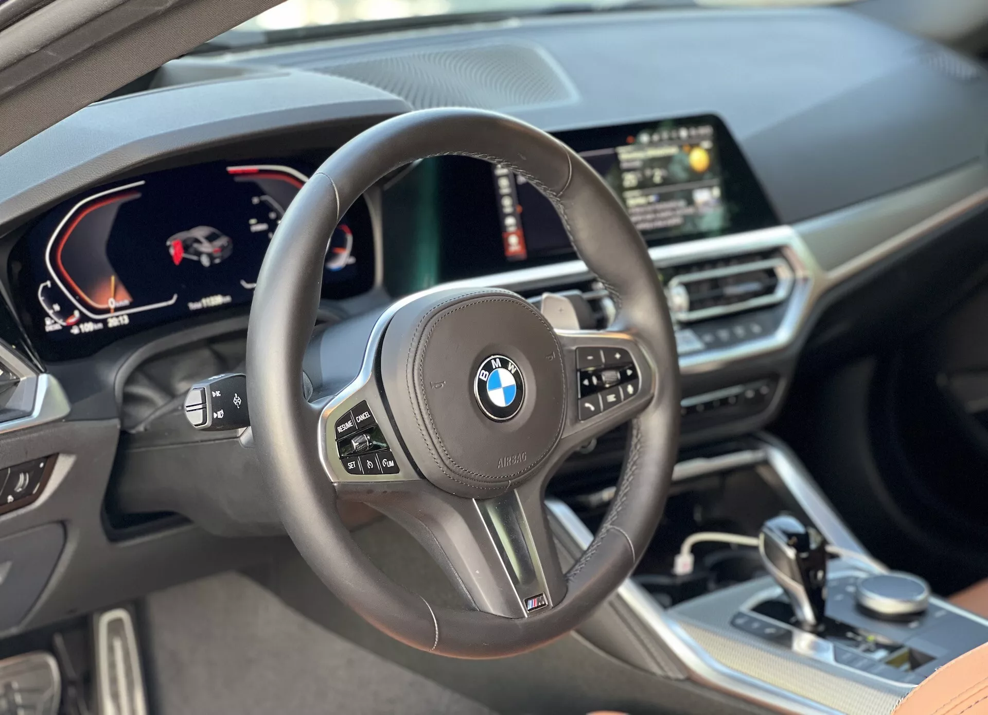 Pohľad na interiér BMW 2er-reihe 2022 z pohľadu vodiča, s centrálne umiestneným volantom s multifunkčnými ovládacími prvkami, digitálnou prístrojovou doskou so tachometrom a rýchlomerom, centrálne digitálnym displejom s GPS navigáciou a prémiovými materiálmi vrátane kožených povrchov a starostlivo navrhnutými ozdobnými prvkami v kabíne.