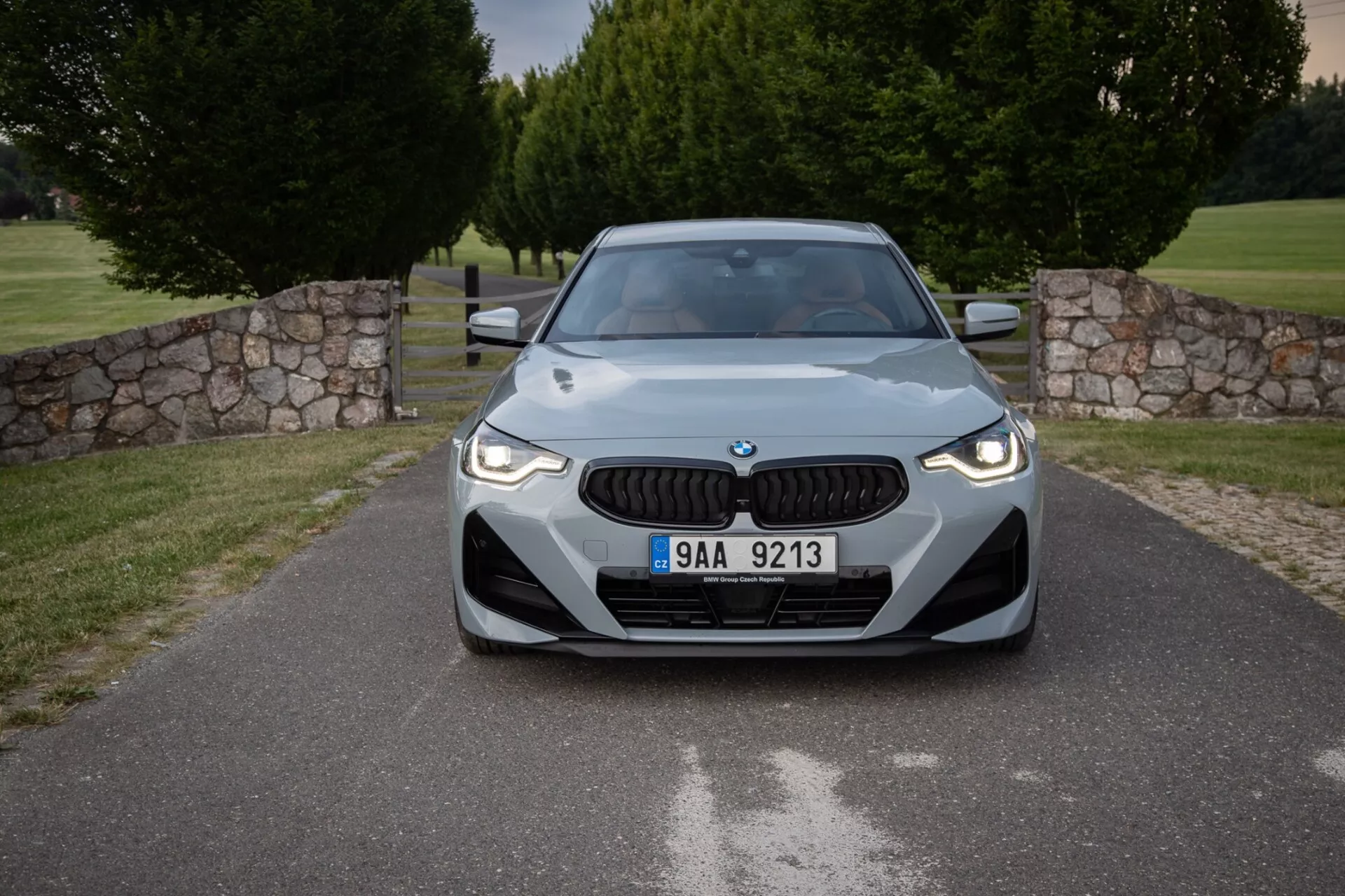 Čelný pohľad na BMW 2er-reihe 2022 (2-series-coupe) v upravenom vonkajšom priestore s charakteristickou mriežkou, elegantnými LED svetlami a aerodynamicky tvarovanou kapotou, všetko zdôrazňujúce moderný dizajn a technologické prvky, vrátane potenciálnych snímačov pre pokročilé systémy asistencie vodiča.