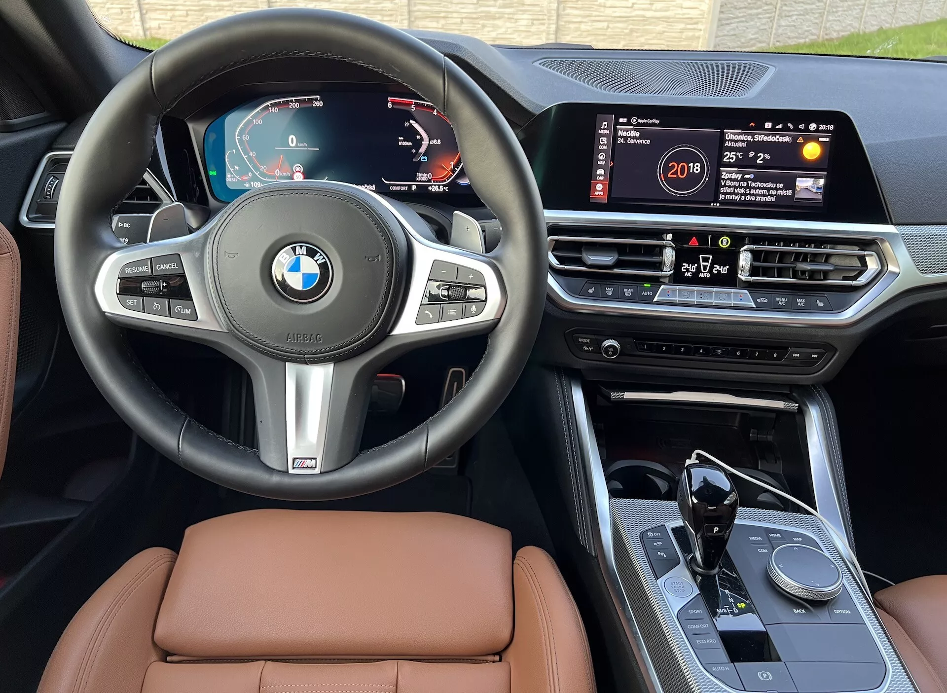 Záber interiéru BMW 2er-reihe 2022 ukazuje palubnú dosku, volant a stredovú konzolu. Medzi funkcie patrí digitálny prístrojový panel, multifunkčný volant, veľký dotykový infotainment systém, otočné ovládacie koliesko na stredovej konzole, automatická radiaca páka so športovým dizajnom a vysoko kvalitné kožené sedačky, všetko z perspektívy sedadla vodiča na dennom svetle.