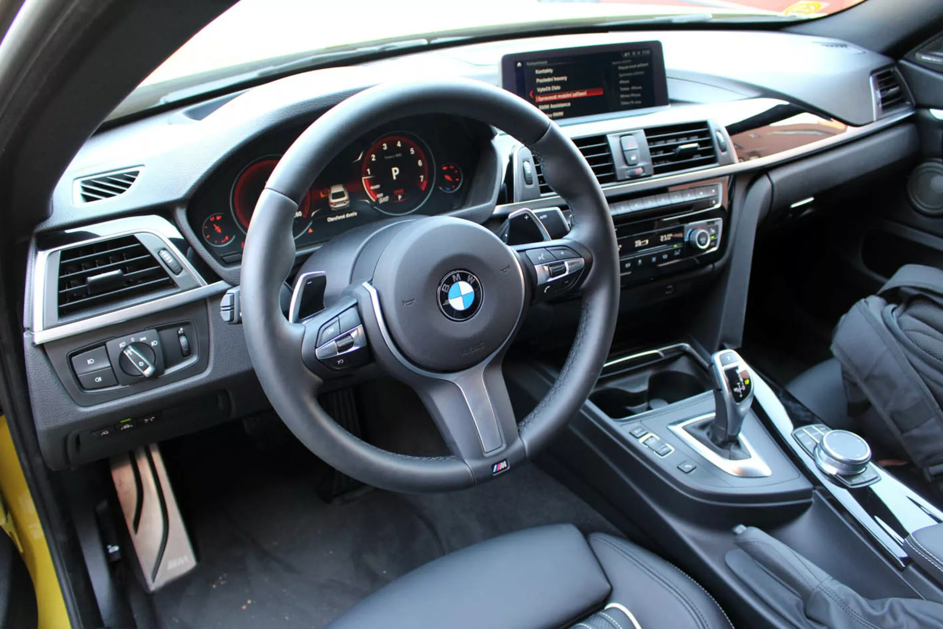 Interiérový pohľad na BMW radu 4 Coupe z roku 2013 z perspektívy vodiča ukazujúci volant, prístrojovú dosku, stredovú konzolu s multimediálnym a klimatizačným ovládaním, páku radenia a luxusné dokončenie