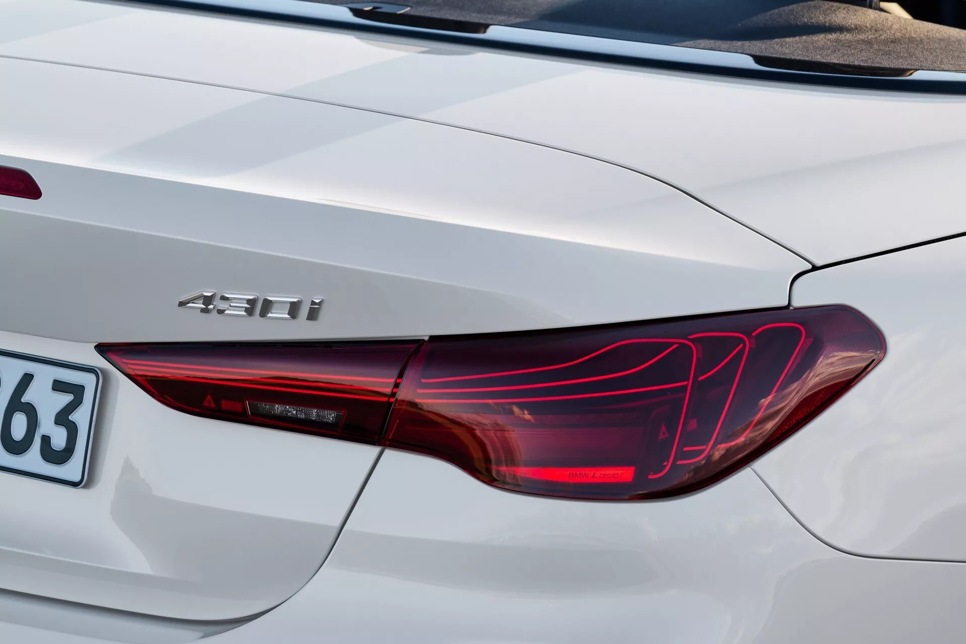 Detailný záber zadného rohu BMW radu 4 2024 (G22-G23-G26-G82-G83-Facelift) so svetlom LED zadného svetla, odznakom hybridu '450h' a časťou kufra v strieborno-bielej farbe
