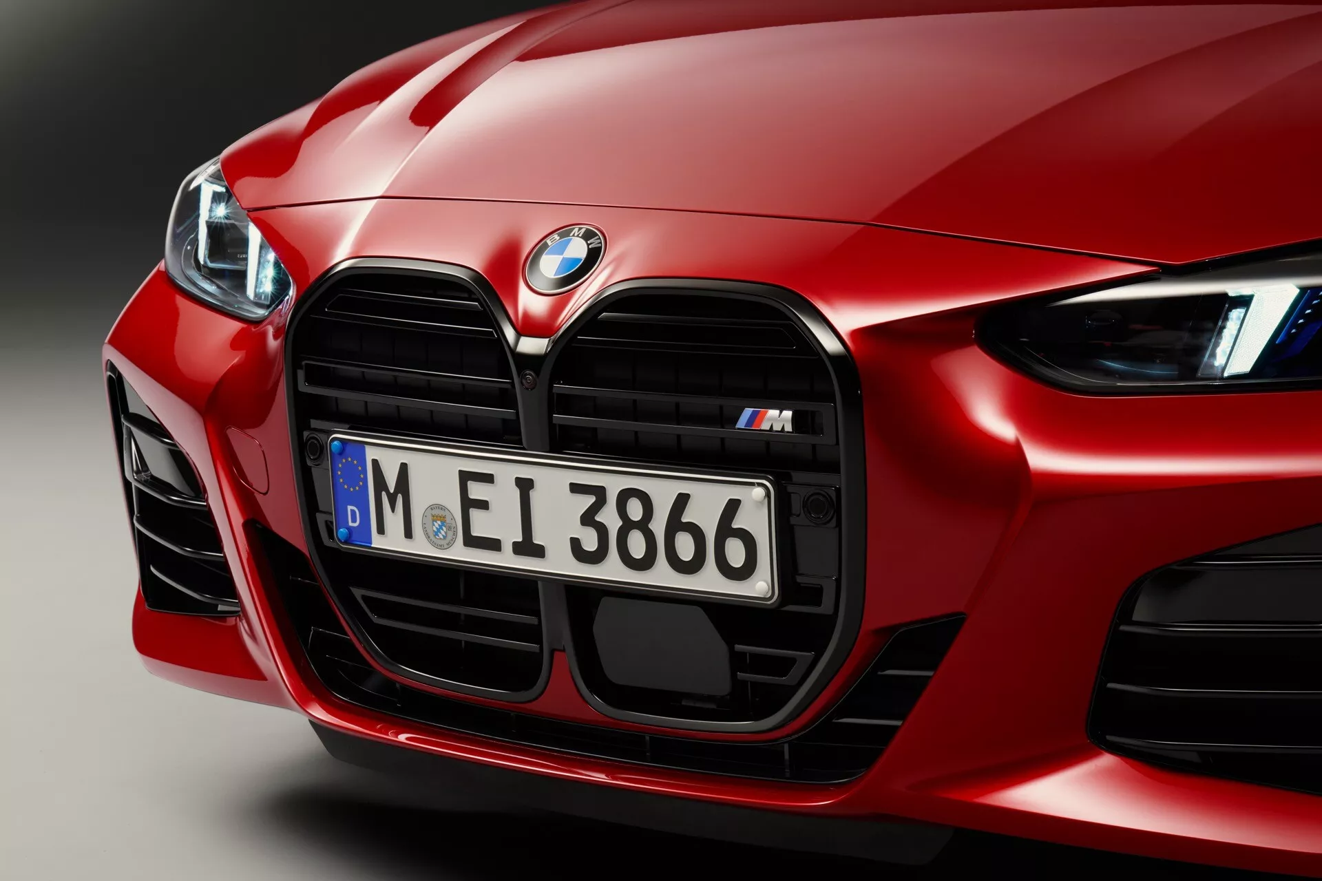Detailný záber na prednú časť červeného BMW 4 série 2024 (G22-G23-G26-G82-G83 Facelift), zdôrazňujúci jeho aerodynamický dizajn, výrazný ľadvinkový gril série M s chrómovými detaily, výkonnostne orientované veľké prívody vzduchu a špičkové LED svetlomety