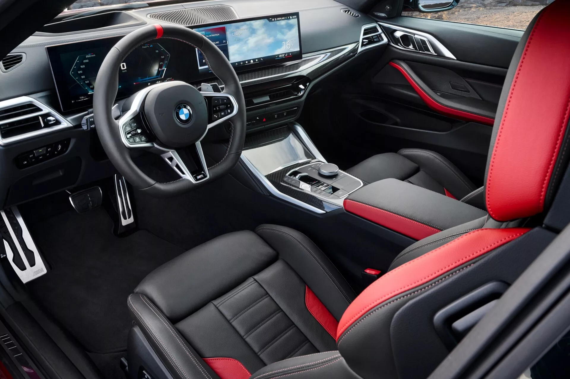 Interiér BMW radu 4 (G22-G23-G26-G82-G83 Facelift) na rok 2024 z pohľadu vodiča s športovými čiernymi koženými sedadlami s červenými akcentmi, multifunkčným volantom, elegantnou palubnou doskou s digitálnymi displejmi a sofistikovanou stredovou konzolou