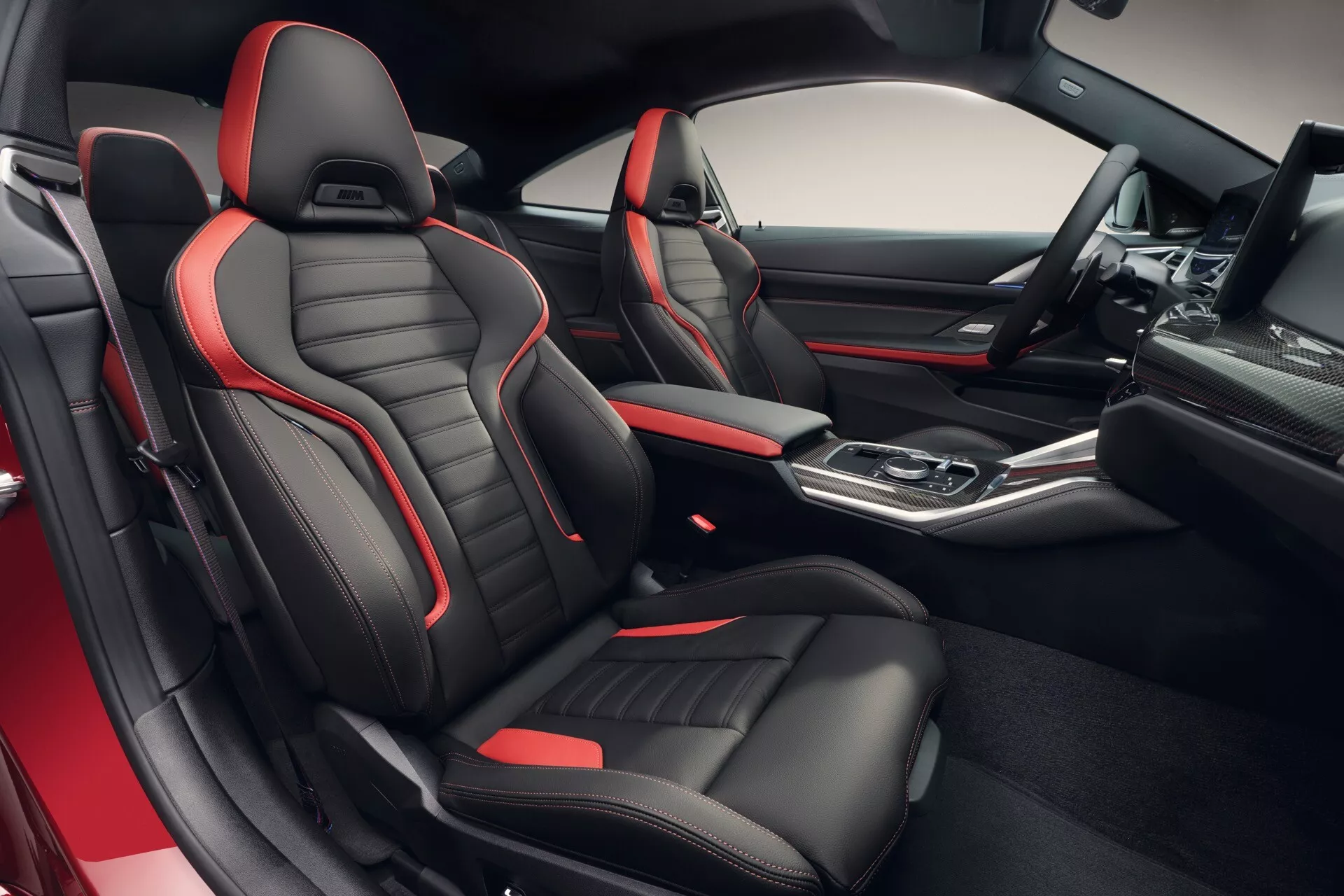 Pohľad do interiéru BMW radu 4 rok 2024 (G22-G23-G26-G82-G83 Facelift) prezentujúci športové sedadlá s čierno-červeným poťahom, hi-tech stredovú konzolu s automatickou radiacou pákou a prémiové funkcie palubnej dosky