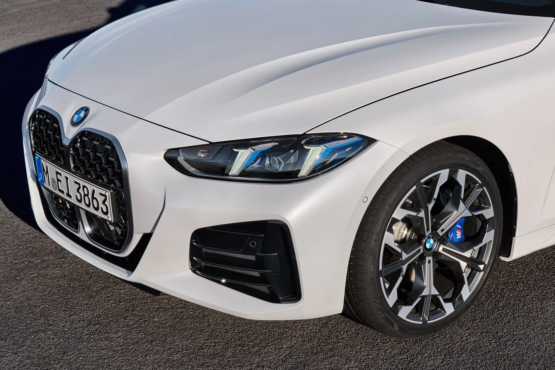 Detailný pohľad na BMW radu 4 2024 (G22-G23-G26-G82-G83 facelift) zobrazujúci predný ľavý kvadrant, s charakteristickou obličkovitou mriežkou, LED svetlometmi, veľkými vstupmi vzduchu na spodnom nárazníku ukazujúcimi výkonnostne orientovaný model a viacramenným kolesom s pokročilým brzdným systémom, všetko z nízkeho, zospodu smerujúceho uhla zdôrazňujúceho športové a luxusné dizajnové prvky auta.