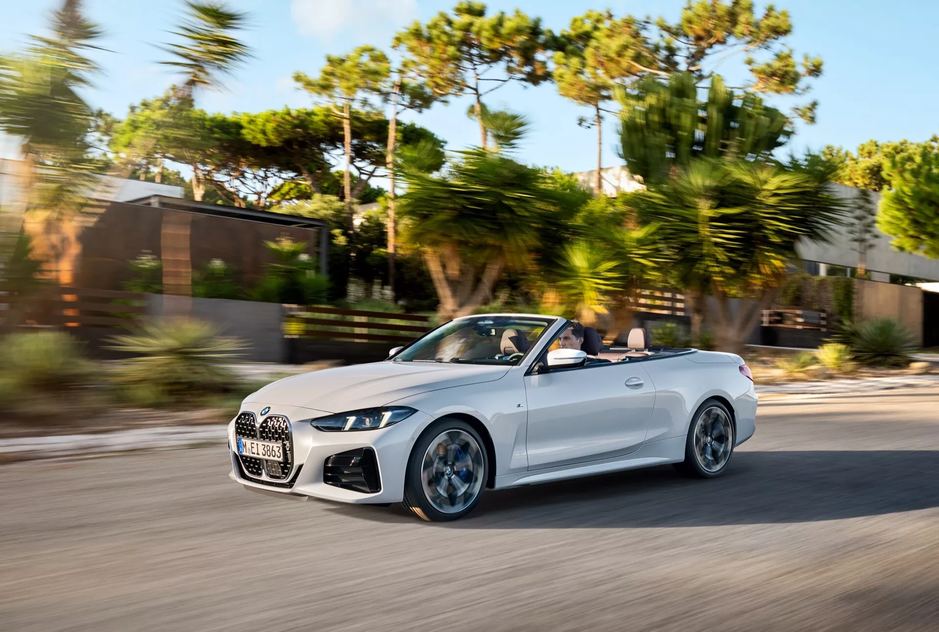 Kabriolet BMW radu 4 2024 (facelift G22-G23-G26-G82-G83) v pohybu, zachytený z uhla tri štvrtiny spredu s dôrazom na aerodynamiku, prémiovú mriežku a LED svetlomety na slnečný deň s rozostreným pozadím.