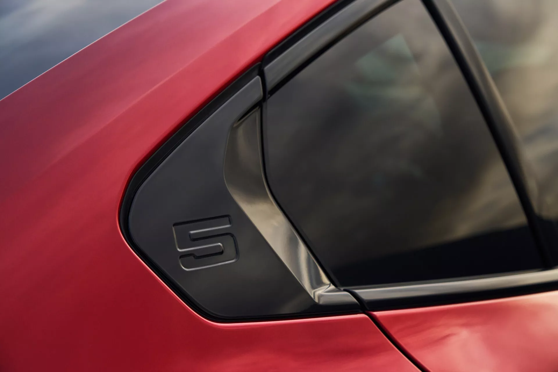 Detailný záber na červené auto BMW radu 5 (G60-G61) so zameraním na oblasť C-stĺpika s výrazným trojuholníkovým oknom a štýlovým dizajnom karosérie