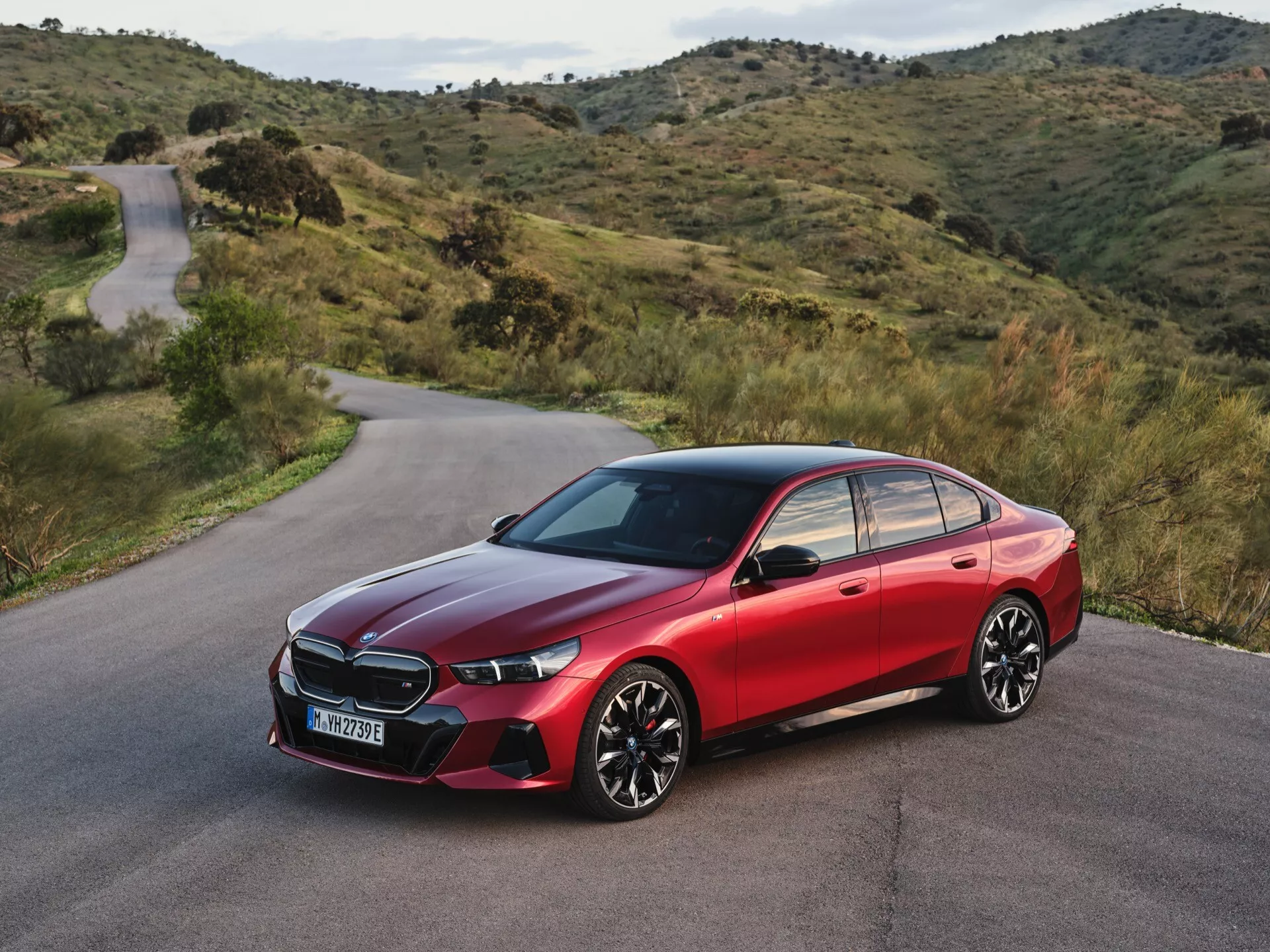 Moderný sedan BMW radu 5 (G60-G61) rok 2023 s tvarovanými líňami, LED svetlometmi a športovým profilom na kopcovitej ceste, zdôrazňujúci luxus a pokročilú technológiu