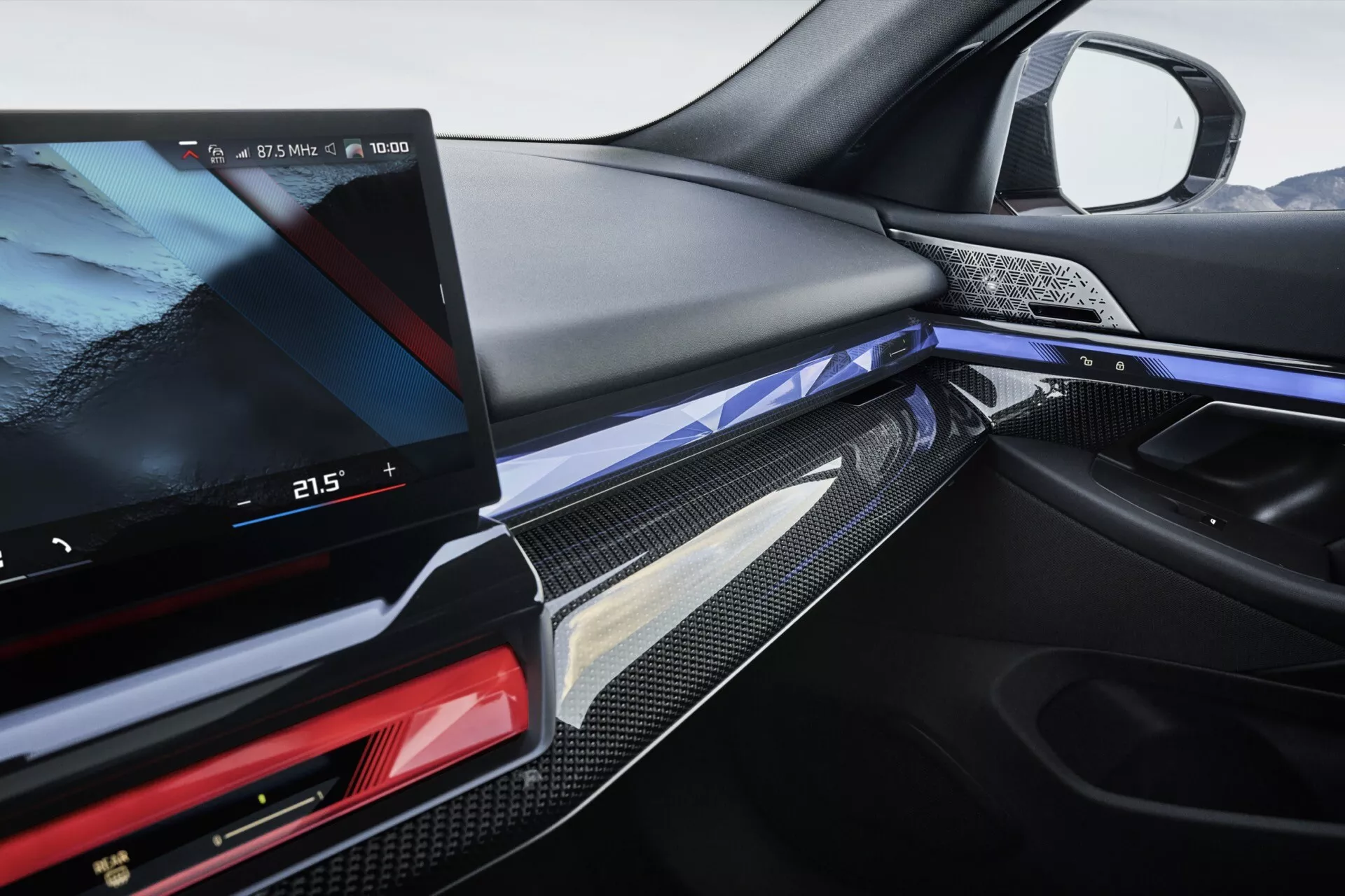 Detailný pohľad na interiér BMW radu 5 (G60-G61) 2023, zdôrazňujúci palubnú dosku na strane vodiča s digitálnym displejom infotainmentu, ozdobnými prvkami z uhlíkových vlákien a športovým volantom.
