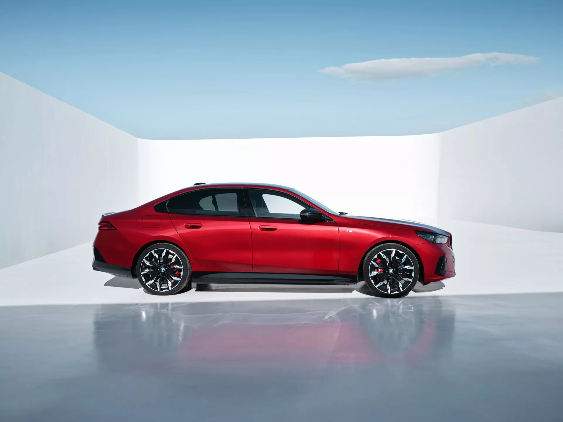 Červený sedan BMW radu 5 (G60-G61) so štyrmi dverami v štúdiovom prostredí so zrkadlovou podlahou, zobrazujúci bočný profil, moderný dizajn a pokročilé vlastnosti