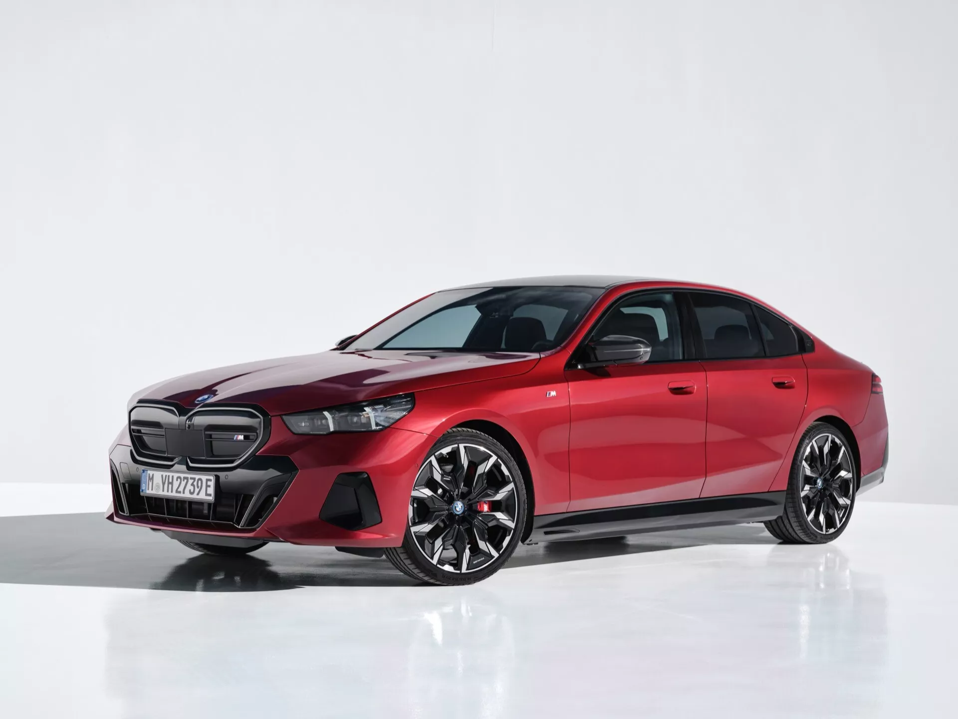 Červené BMW radu 5 (G60-G61) 2023, záber z polovice štúdia ukazujúci LED svetlomety, veľkú prednú masku, aerodynamické zliatinové kolesá a nízkoprofilové pneumatiky z trojštvrtečného predného pohľadu