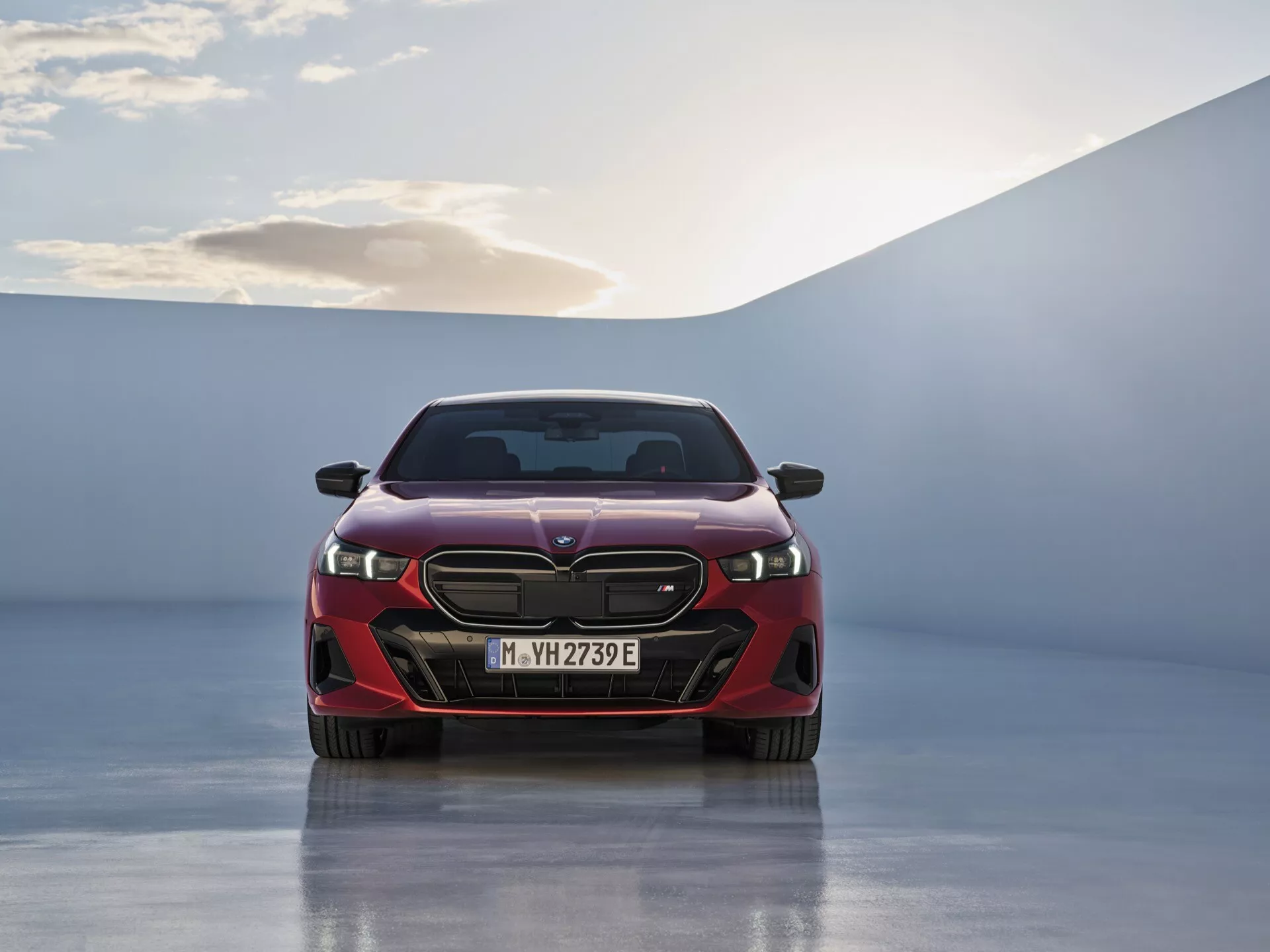 Predný pohľad na BMW série 5 2023 (G60-G61) predvádzajúci LED svetlomety, zložitý mriežku a označenie EV na lesklej podlahe showroomu pod jemným osvetlením