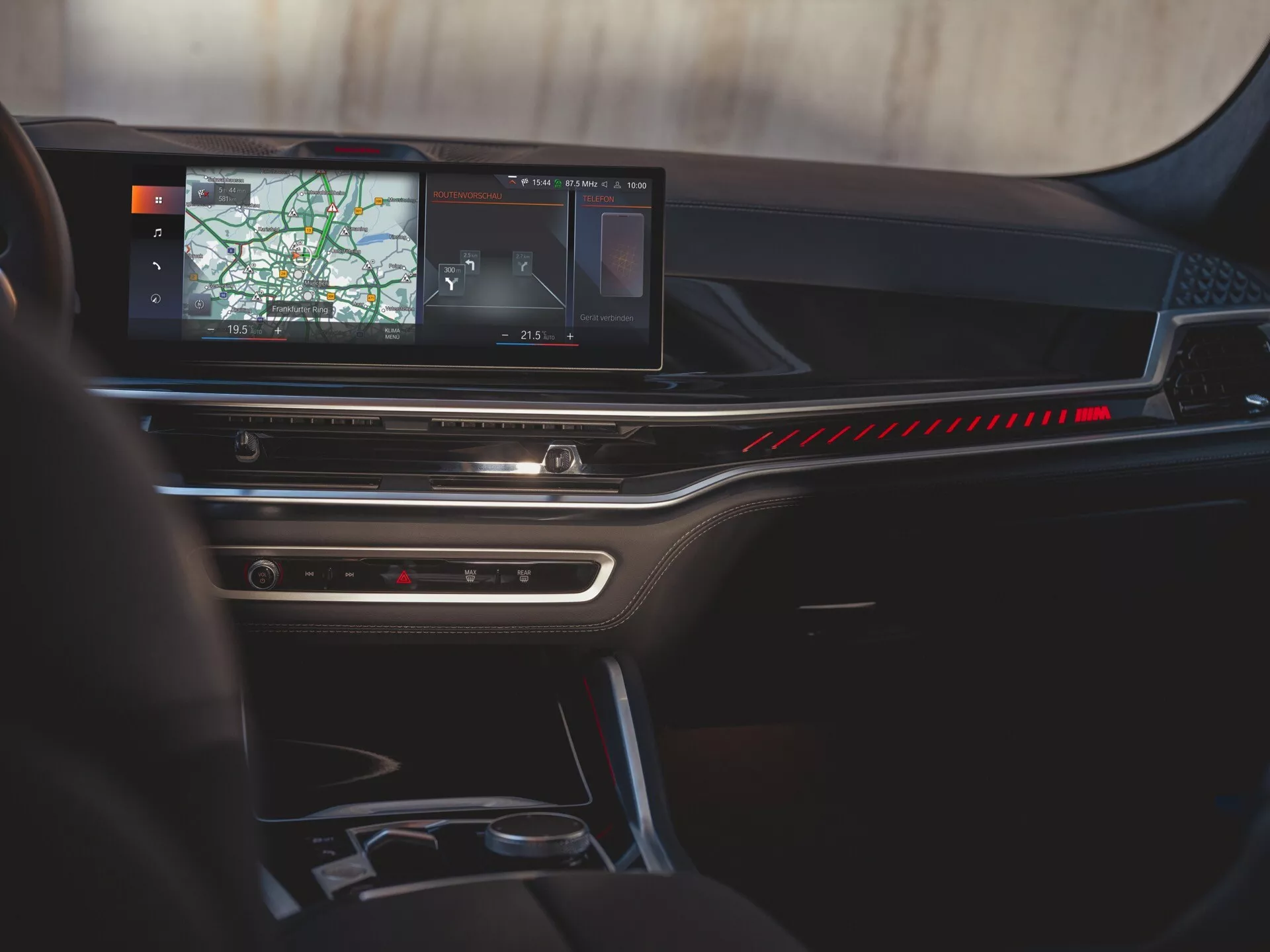 Interiér BMW X6 2023 (G06-F96-facelift) so zameraním na palubnú dosku, veľkú obrazovku infotainmentu zobrazujúcu navigáciu a elegantný panel klimatizácie z pohľadu zadného pasažiera