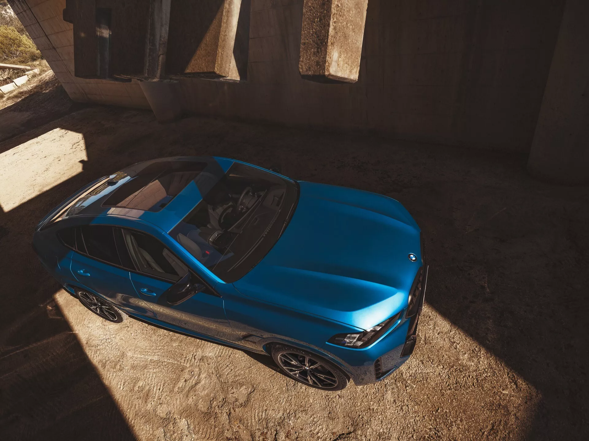 BMW X6 2023 (G06-F96-facelift) odfotografované z vysokého uhla, predvádzajúce svoj elegantný, aerodynamický profil a živú modrú farbu v modernom dizajne