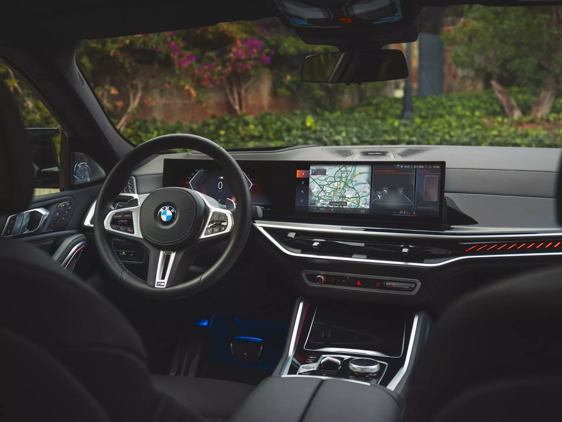 Interiér BMW X6 2023 (G06-F96-Facelift) z pohľadu vodiča, zdôrazňujúci športový volant obalený kožou s ovládaním, vysokorozlíšený displej infotainmentu s navigáciou, luxusné ambientné osvetlenie a sedadlá z prémiovej kože