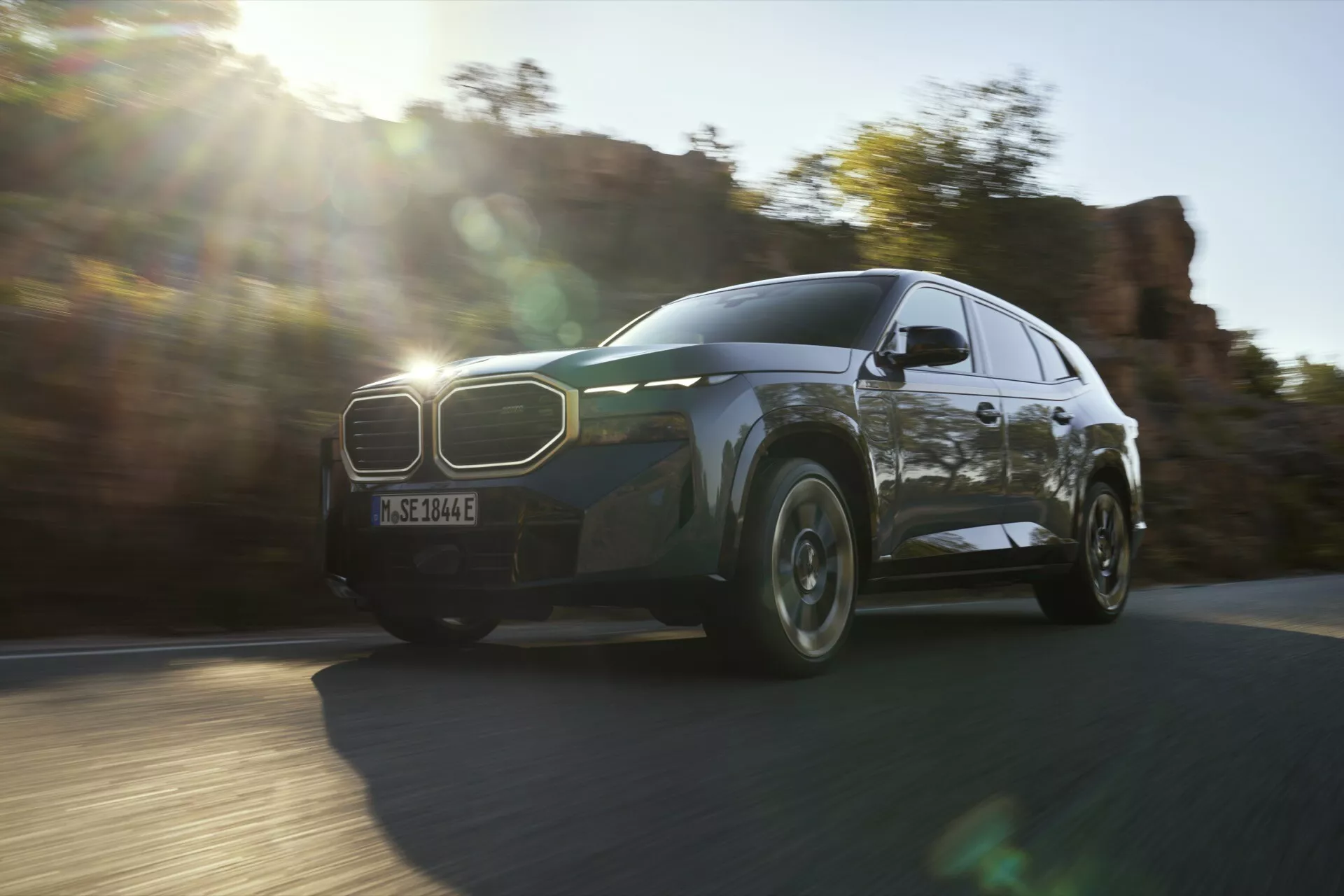 Dynamický pohľad na BMW XM (G09) rok 2023 v pohybe, zvýrazňujúci čelnú ľavú štvrtinu, mriežku, LED svetlomety a dizajn kolesa za prirodzených svetelných podmienok