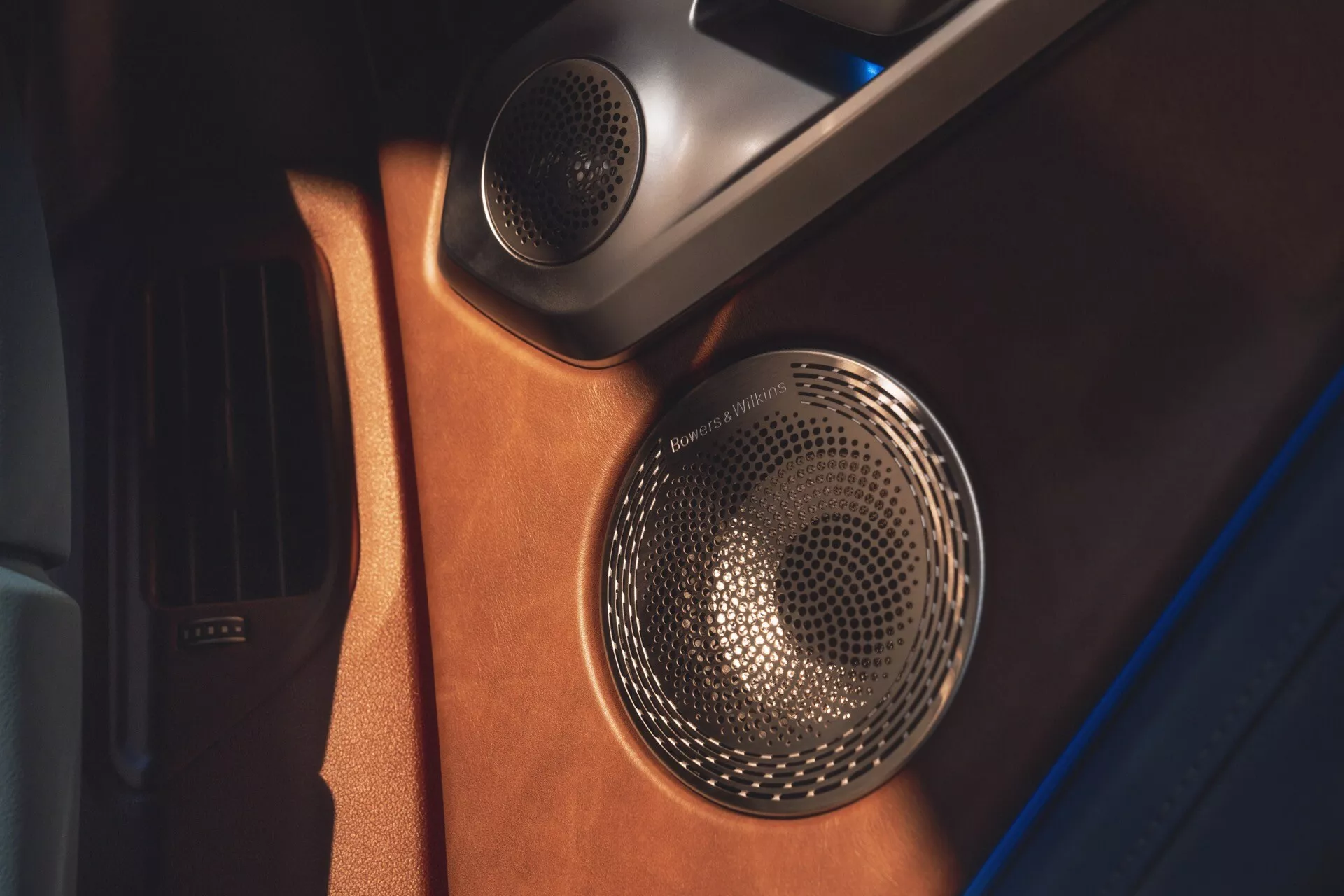Detailný pohľad na dverový panel BMW XM 2023 (G09) s luxusným zvukovým systémom s kovovou mriežkou reproduktora a koženým prevedením