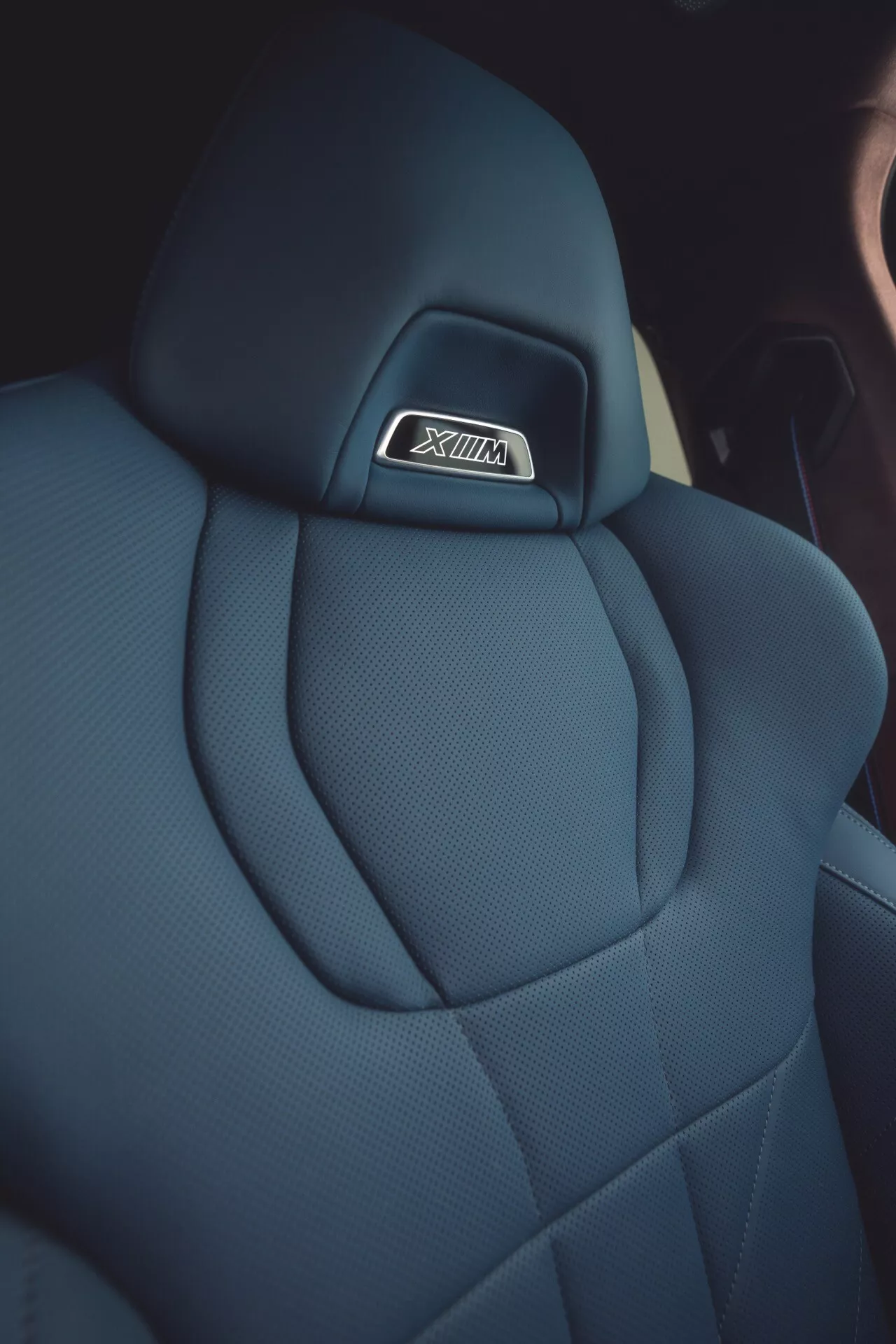 Detailný pohľad na sedadlo auta BMW XM 2023 (G09), ktoré ukazuje prvotriednu tmavú látkovú opierku hlavy s logom SRT, šitie s diamantovým vzorom a ergonomický dizajn zdôrazňujúci luxus a výkon.