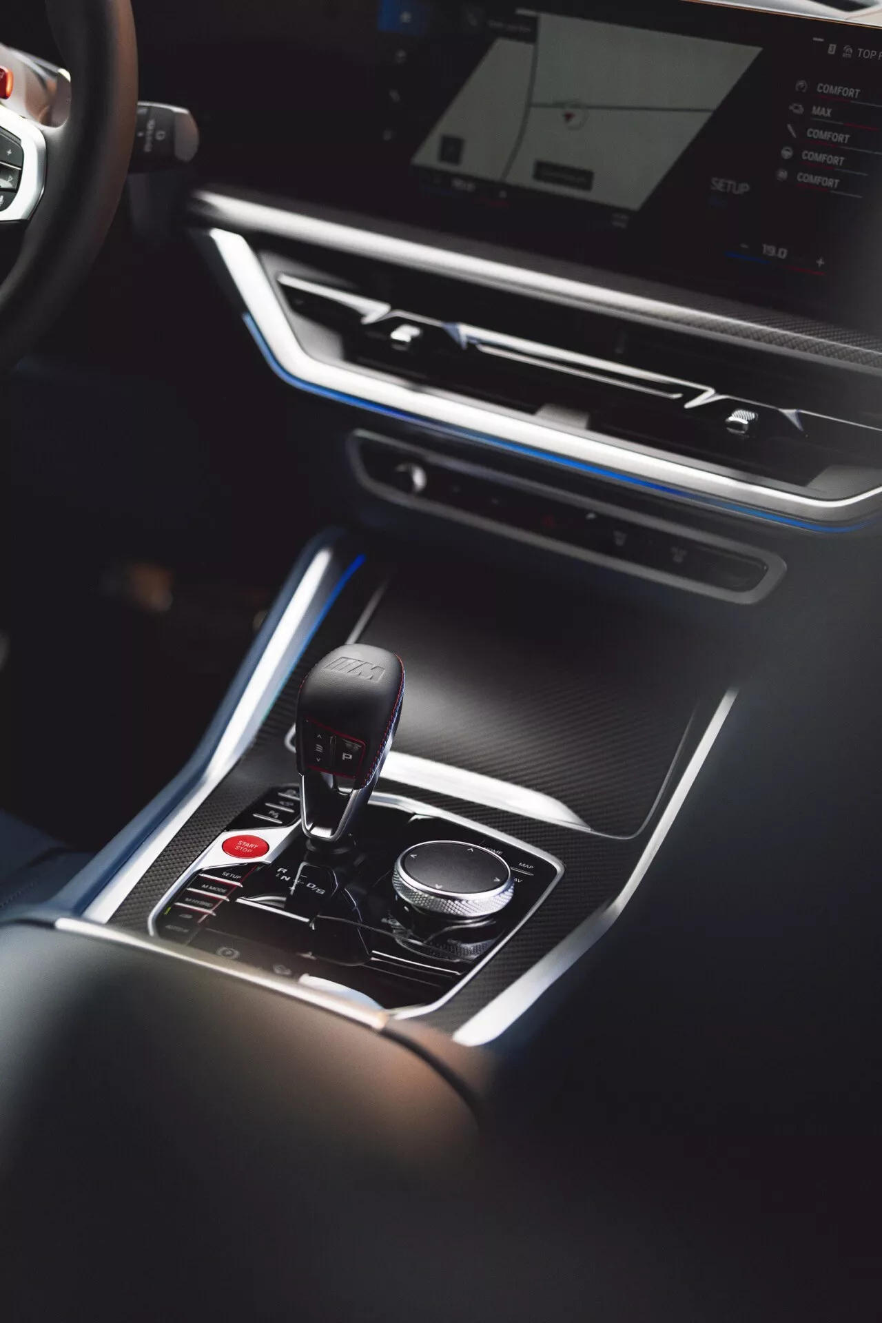 Pohľad zhora na interiér BMW XM 2023 (G09) so zameraním na stredovú konzolu s automatickou radicou pákou v polohe parkovania, obklopenou luxusnými doplnkami a dotykovým ovládačom multimediálneho systému