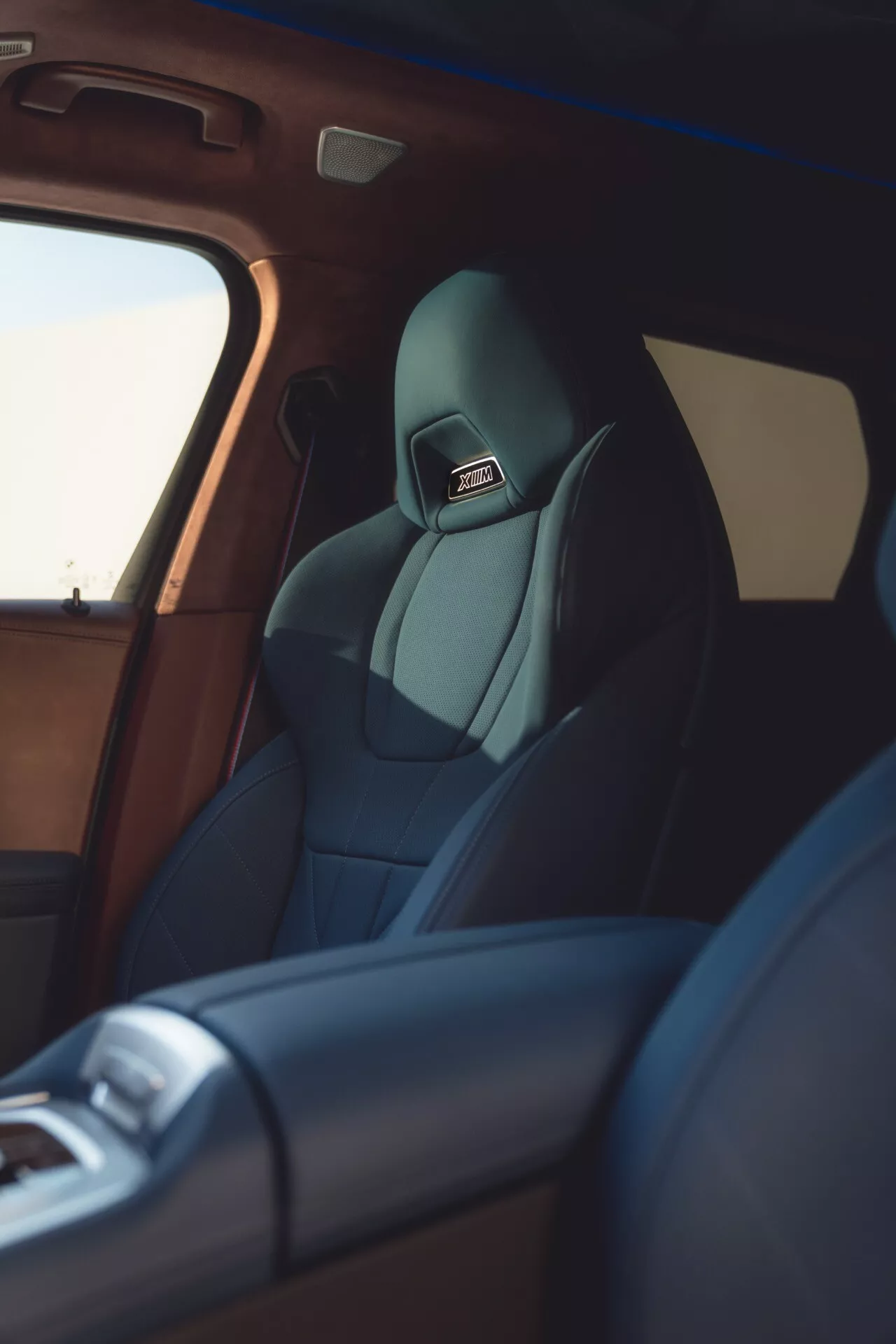 Interiér BMW XM (G09) 2023 so zameraním na sedadlo vodiča a jeho vysokokvalitné čalúnenie z bočnej perspektívy, zdôrazňujúci technologické funkcie a luxusné dokončenie.