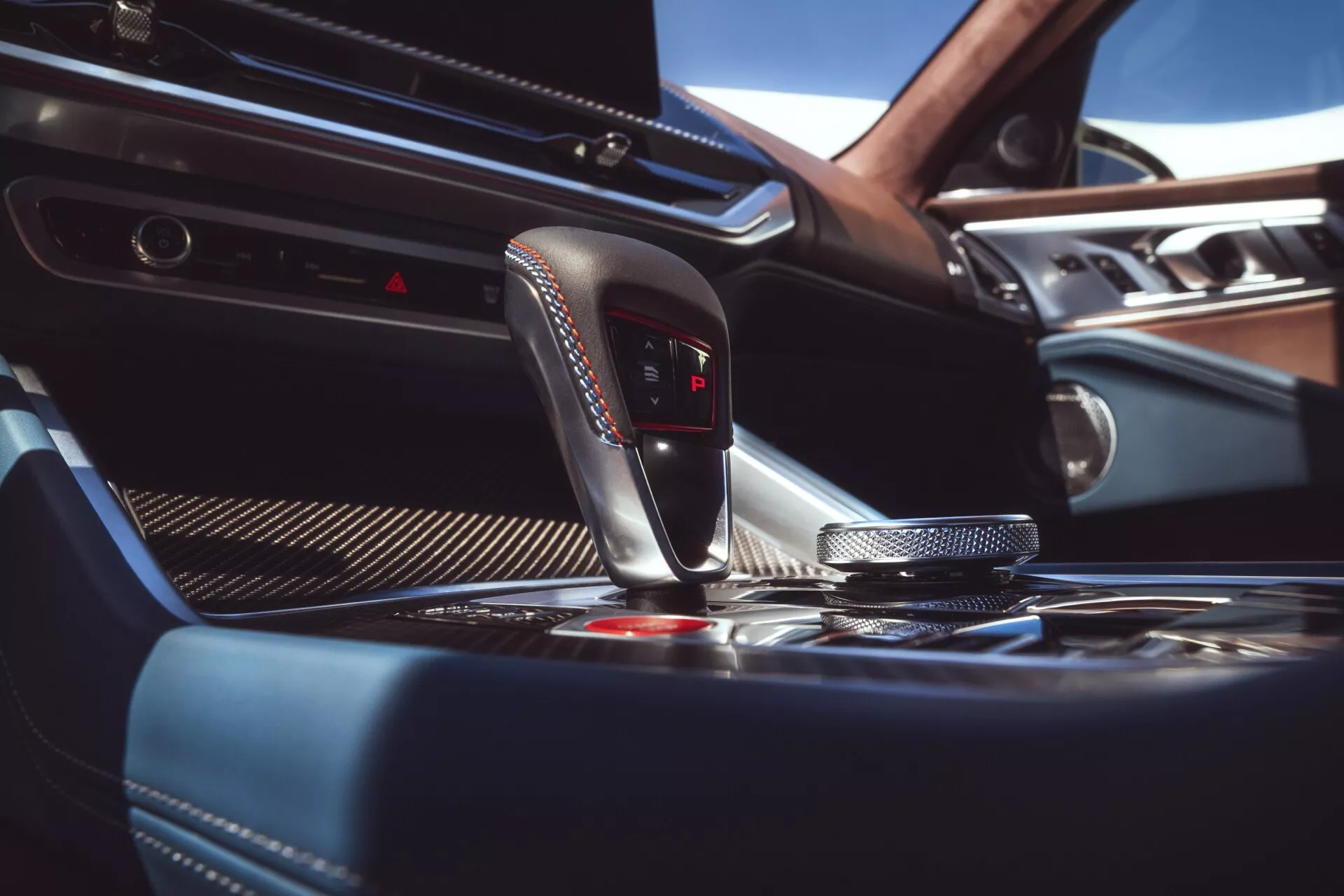 Interiér BMW XM (G09) 2023 s ergonomickou pákou prevodovky s indikátorom parkovania, sofistikovaným obkladaním z uhlíkových vlákien okolo moderného ovládača iDrive, tlačidlom pre bezkľúčové štartovanie a zastavenie, luxusnými povrchmi z dreva a kože a náhľadom na automatický klimatizačný systém