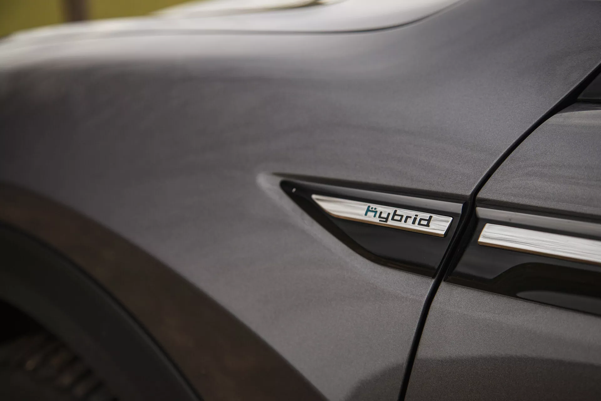 Detailný pohľad na Citroen C5-X 2022 s označením Hybrid na nižšom bočnom profile pri zadnom kolieskovom priestore, prezentujúci hybridnú technológiu a dizajnovú estetiku v mäkkých svetelných podmienkach