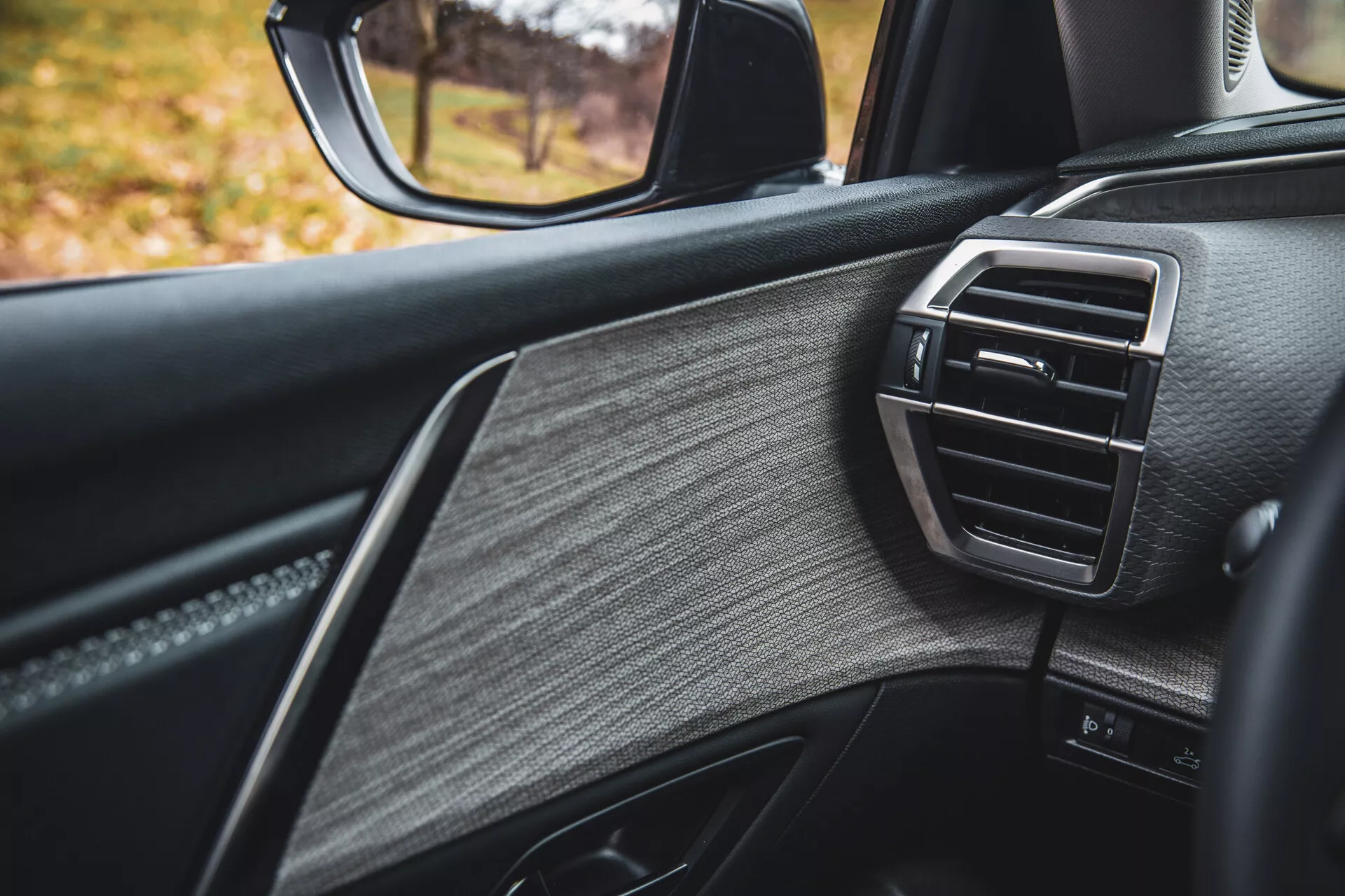 Detailný pohľad na dvere od spolujazdca Citroen C5-X 2022, predvádzajúci luxusný dizajn s textúrovanou kožou, lesklými doplnkami a ventiláciou klimatizačného otvoru