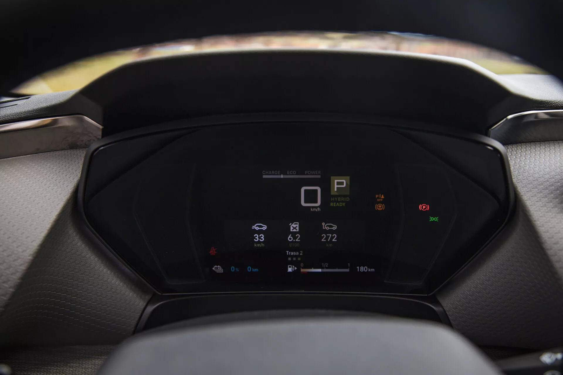 Detailný pohľad na digitálny palubný panel Citroen C5-X 2022 zobrazujúci metriky vozidla, vrátane označenia rýchlosti, tachometra a spotreby energie, s rozmazaným volantom a čelným sklom v popredí a pozadí.