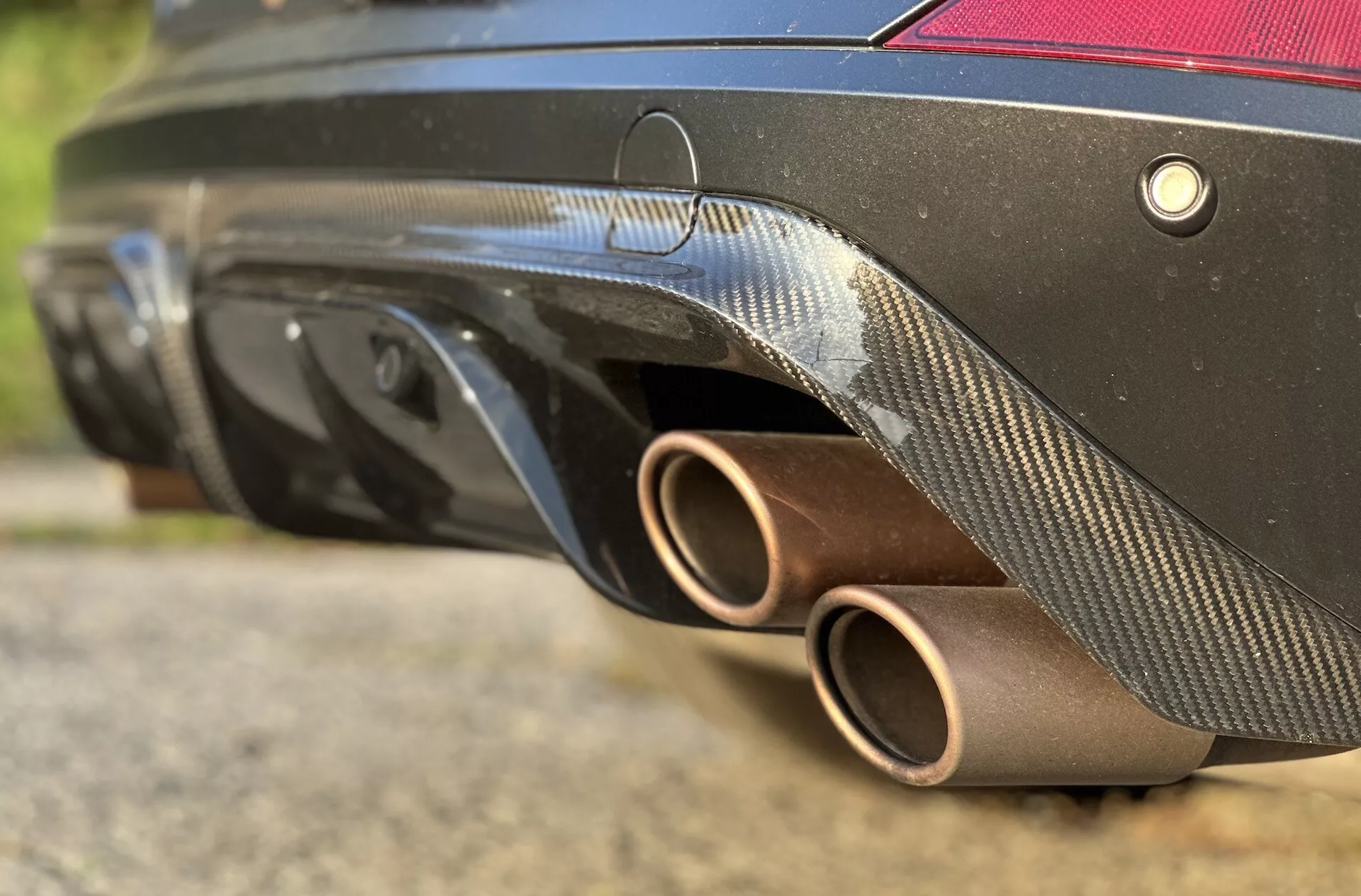 Detailný pohľad na zadnú časť Cupry Formentor 2020, kde vynikajú bronzové výfukové rúry, difúzor z karbónových vlákien, systém senzorov a čierna farba karosérie z nízkeho uhla, čo zdôrazňuje jej športový dizajn a vlastnosti zamerané na výkon