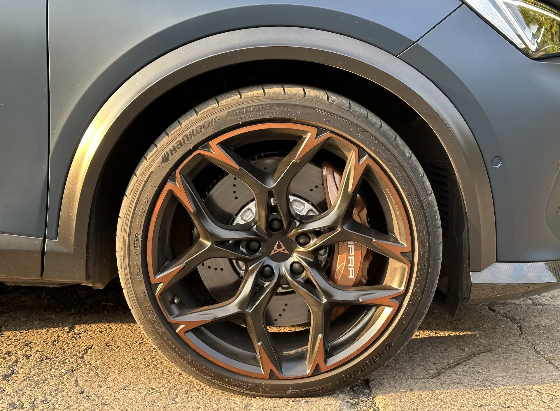 Detailný záber na predné koleso vodičovej strany Cupra Formentor 2020 s viacramenným ráfikom s tmavometalickým povrchom, brzdový strmeň kontrastnej farby a výkonnostné pneumatiky
