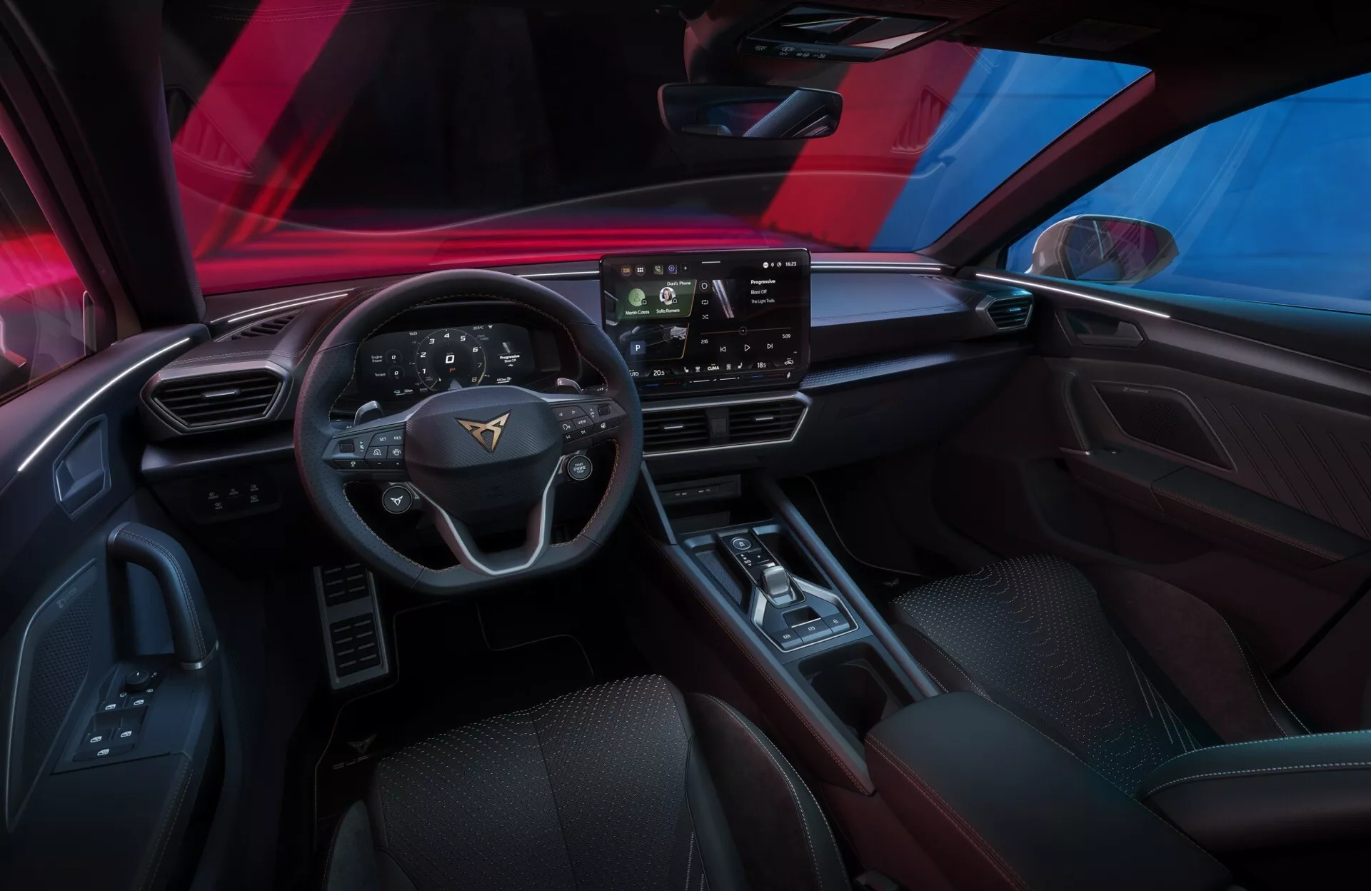 Pohľad na interiér modelu Cupra Leon 2024 (1. generácia facelift) z pohľadu vodiča, ukazujúci palubnú dosku, trojramenný volant s integrovanými ovládačmi, veľký dotykový infotainment displej a stredovú konzolu. Viditeľné funkcie zahŕňajú ovládače okien a zrkadiel, reproduktor, digitálny prístrojový panel alebo head-up displej, minimalistický systém ovládania klímy a pokročilé technológie pre pohodlie, zábavu a asistenciu vodiča.
