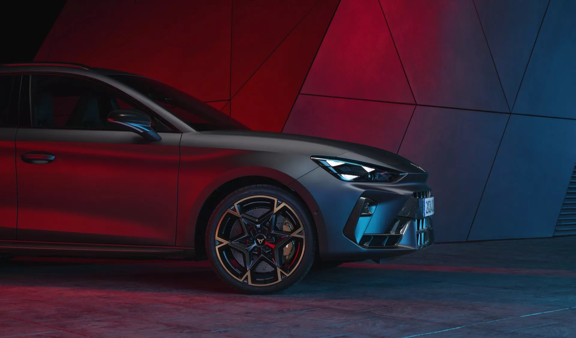 Predný trojštvrťový pohľad na Cupra Leon 2024 (facelift prvej generácie) zdôrazňujúci moderný dizajn s LED svetlami, športovou mriežkou, tvarovaným predným nárazníkom, uhlovými vzduchovými vstupmi, viaclúčovými zliatinovými kolesami a nízkoprofilovými pneumatikami na červenom abstraktnom pozadí.
