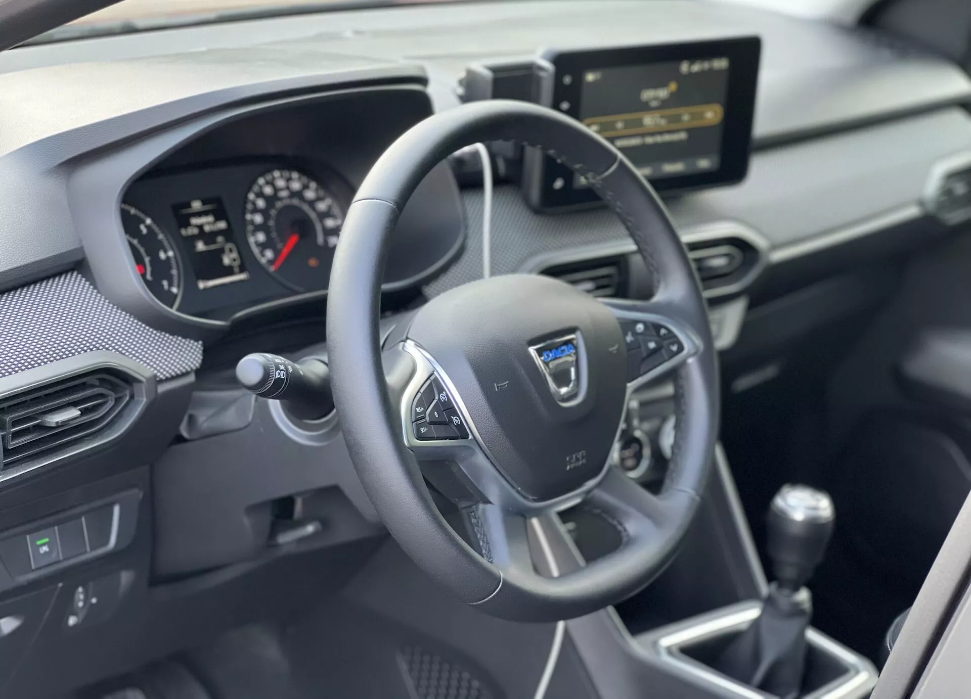 Interiér Dacia Jogger 2022 s dôrazom na oblasť vodiča s trojspojkovým multifunkčným volantom, analógovo-digitálnym prístrojovým panelom, stredovou konzolou s infotainment systémom a manuálnou prevodovkou