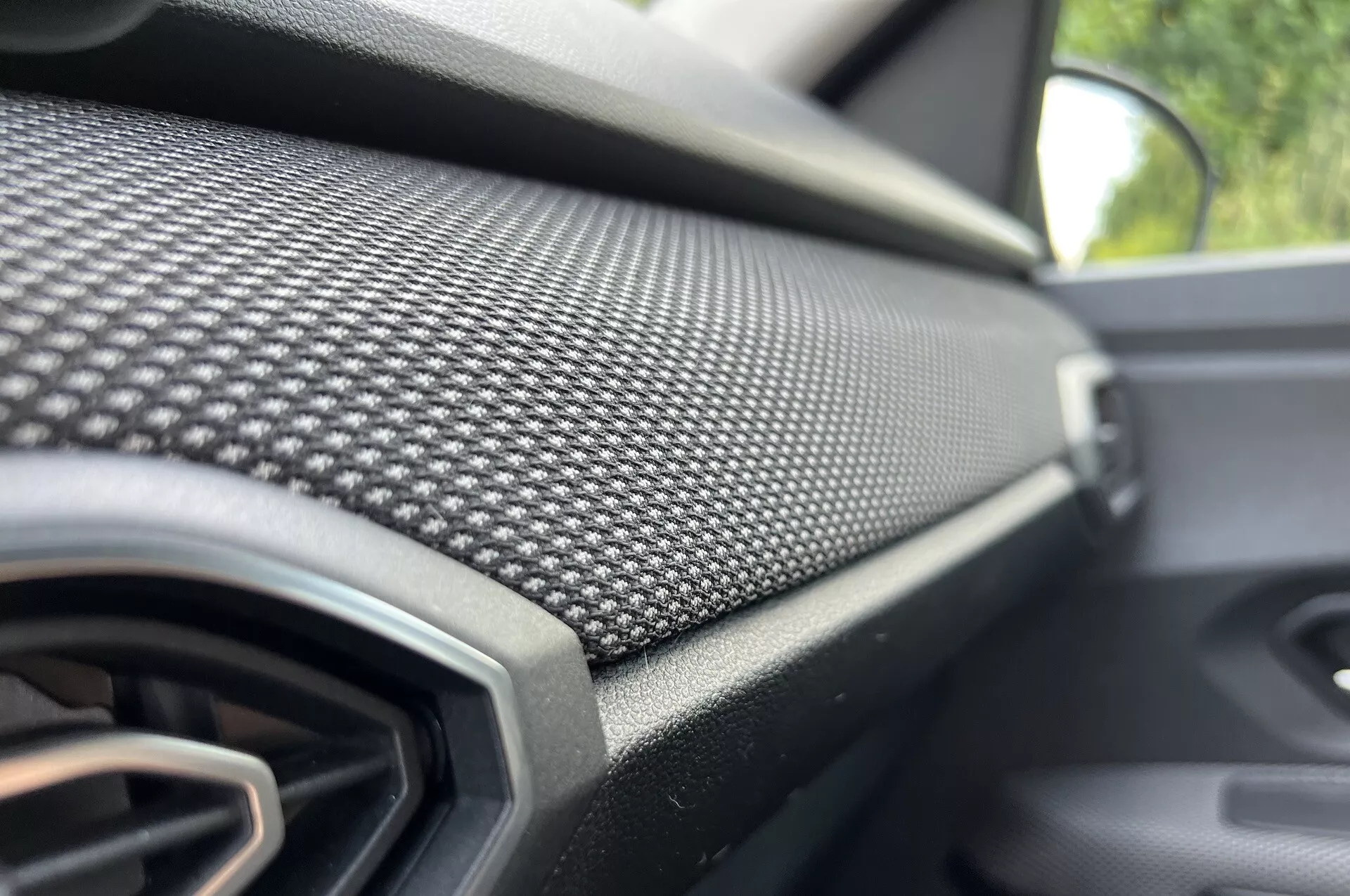 Detailný pohľad na prístrojovú dosku na strane spolujazdca Dacia Jogger 2022 s uhlíkovým vzorom a vetracou mriežkou, zdôrazňujúci moderný dizajn a luxusné prvky