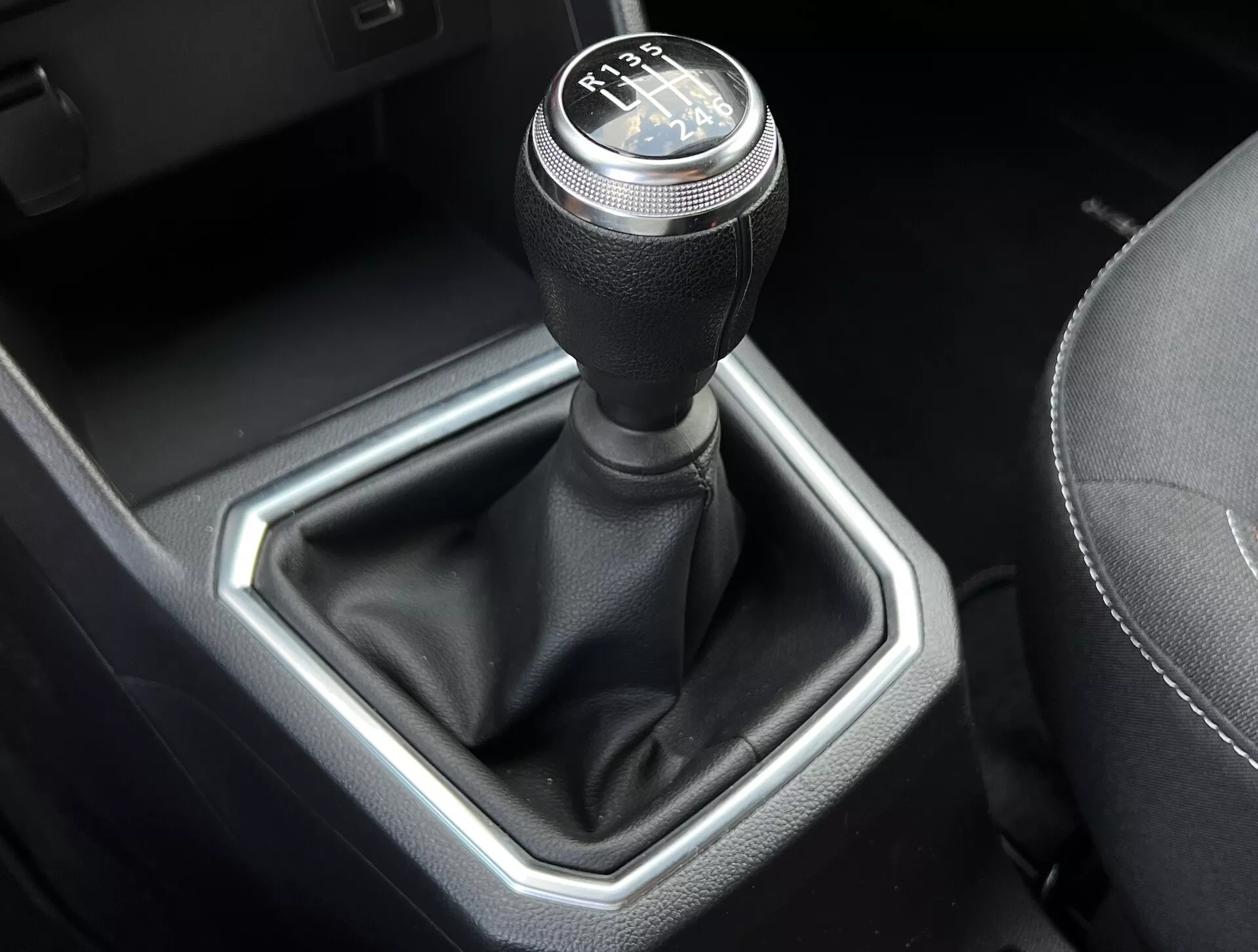 Detailný pohľad na manuálnu prevodovku Dacia Jogger 2022 s 6-rýchlostným radením, koženým krytom páky a kovovou šesťuholníkovou vložkou vo vysoko kvalitnom interiéri vozidla