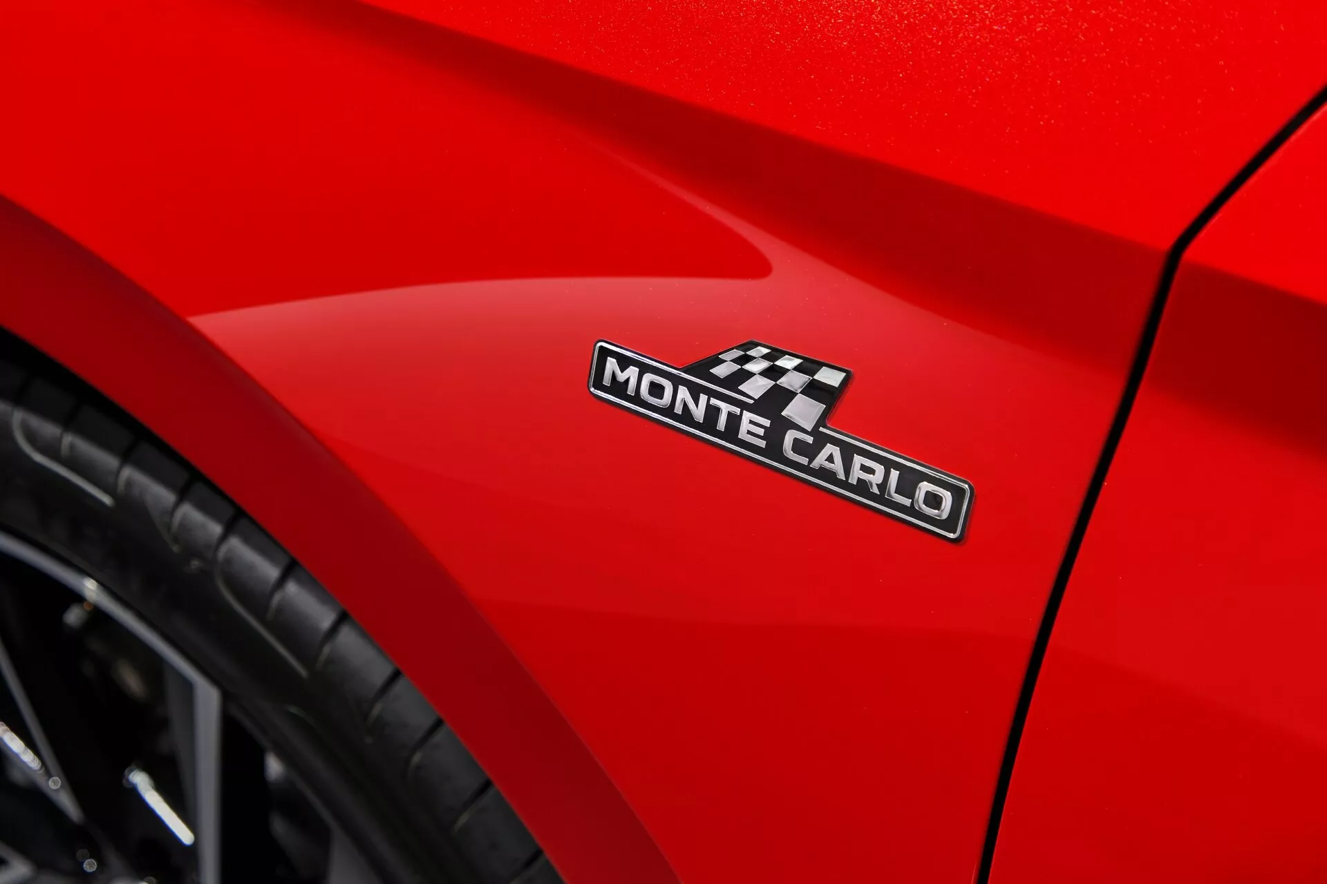 Detailný pohľad na Dacia Sandero Stepway 2020 s žiarivo červenou karosériou zameraný na emblém MONTE CARLO a štýlovú krivku pri zadnom kolese, zhotovený z nízkeho uhla