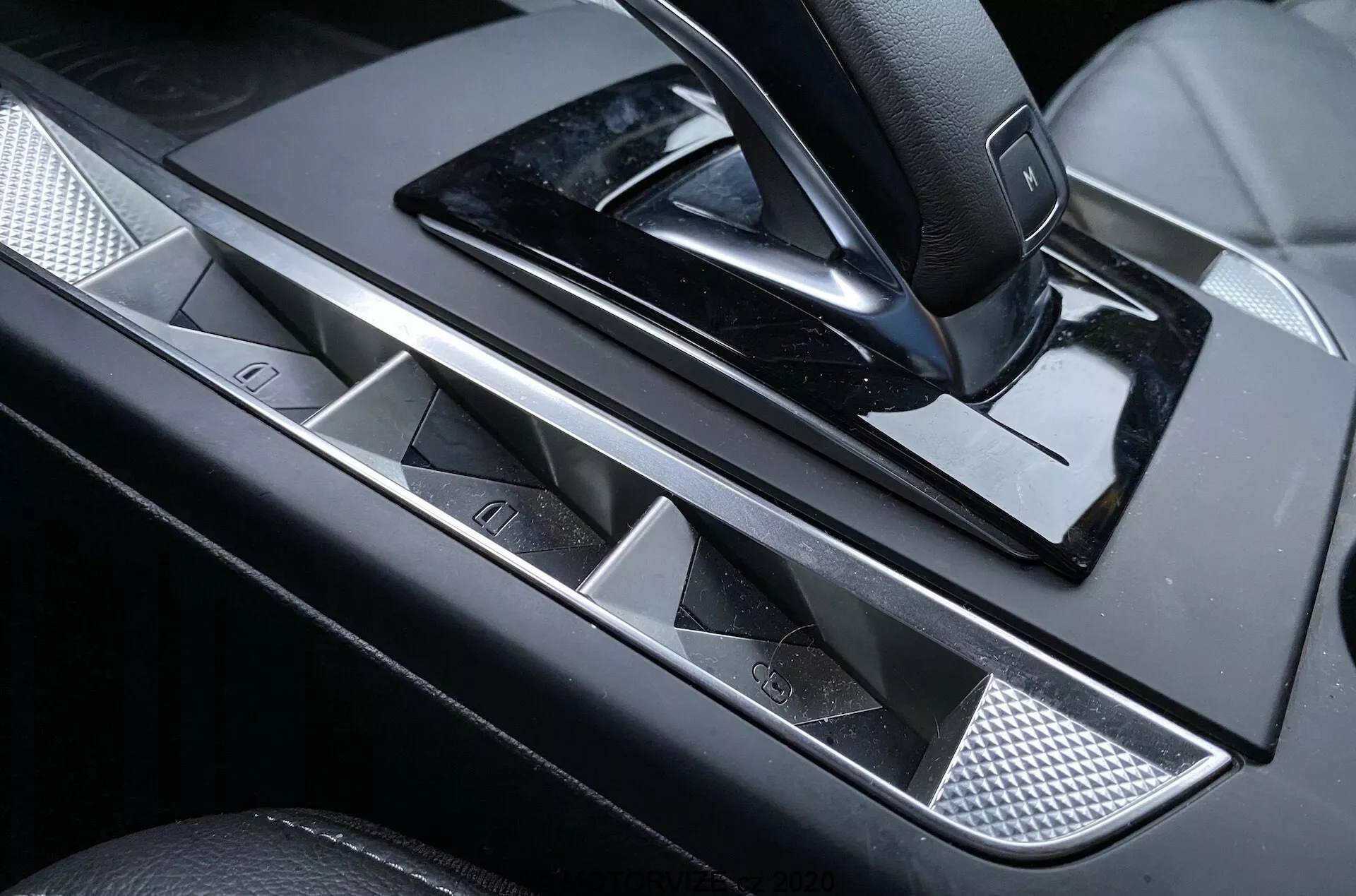 Detailný pohľad na ovládací panel dverí vodiča luxusného DS Automobiles DS-3 Crossback z roku 2019, s elegantnou kovovou kľučkou, tlačidlami elektrických okien s chrómovými akcentmi, joystickom na nastavenie zrkadiel, lesklým čiernym dekorom a štruktúrovanou kovovou sieťovinou pre dotyk sofistikovanosti.