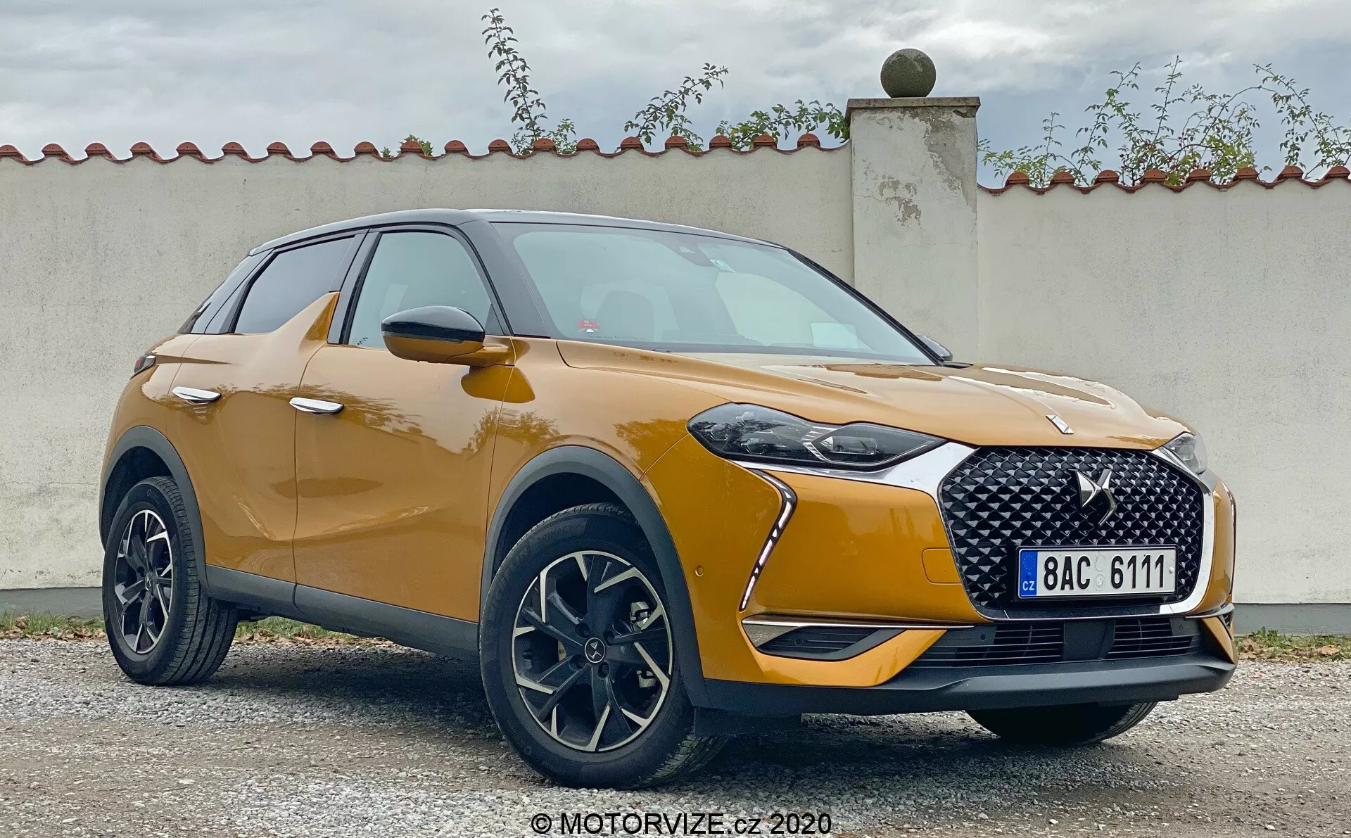 Predný trojštvrťový pohľad na model DS Automobiles DS 3 Crossback 2019. Obrázok zobrazuje moderné SUV crossover s výraznou mriežkou, elegantnými LED svetlometmi a puzdrami na hmlové svetlá. Metalická farba, hladké kontúry kapoty a zliatinové kolesá zdôrazňujú športový, no zároveň luxusný dizajn. Aerodynamicky navrhnuté bočné zrkadlá s integrovanými smerovými svetlami a plastové obloženie okolo oblúkov kolies prispievajú k robustnej estetike vozidla.