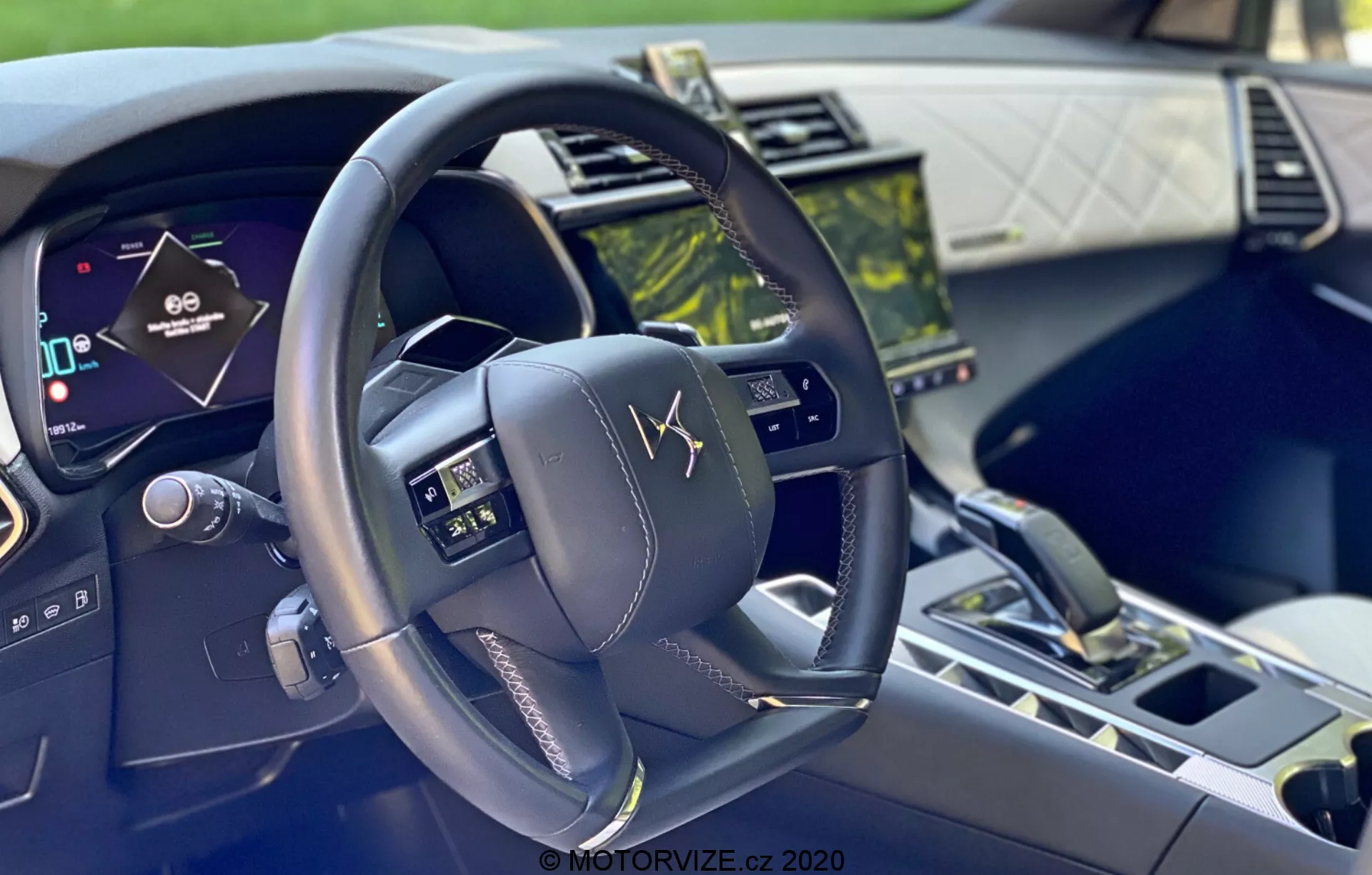 Interiérový záber vozidla DS-7 Crossback 2018 z pohľadu vodiča, zobrazujúci moderný, multifunkčný volant s ovládacími tlačidlami, digitálnu prístrojovú dosku a dotykový infotainment systém, zdôrazňujúci pokročilú technológiu a luxusné materiály.