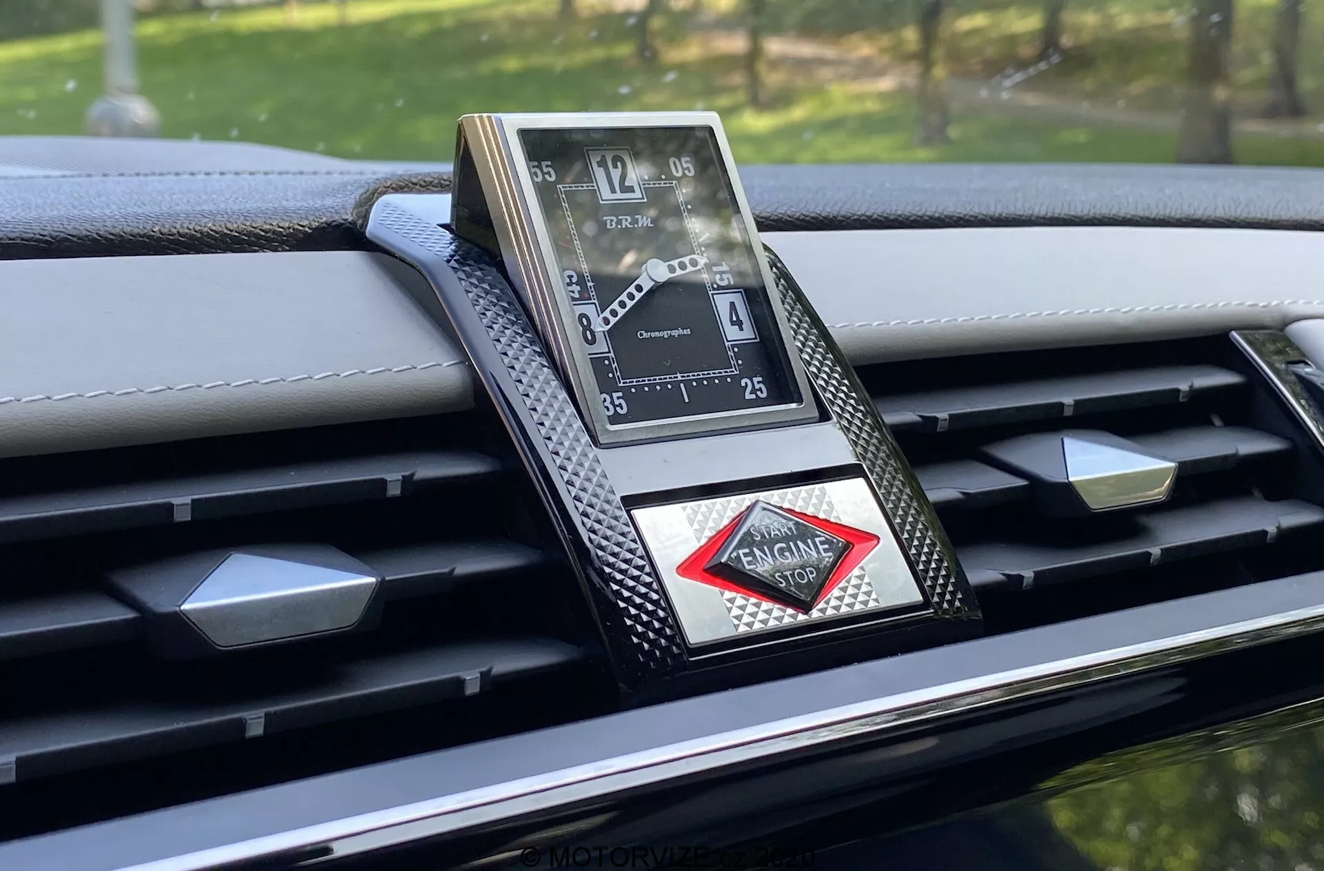 Detailný záber na luxusné analógové hodiny zabudované v palubnej doske DS-7 Crossback 2018, ktoré sa vyznačujú sofistikovaným dizajnom s rímskymi číslicami, kovovým povrchom a logom v tvare diamantu. Palubná doska obsahuje karbónové akcenty a podrobné prešívanie, čo zdôrazňuje vysoko kvalitné remeselné spracovanie a pokročilé materiály v tomto prémiovom interiéri automobilu.