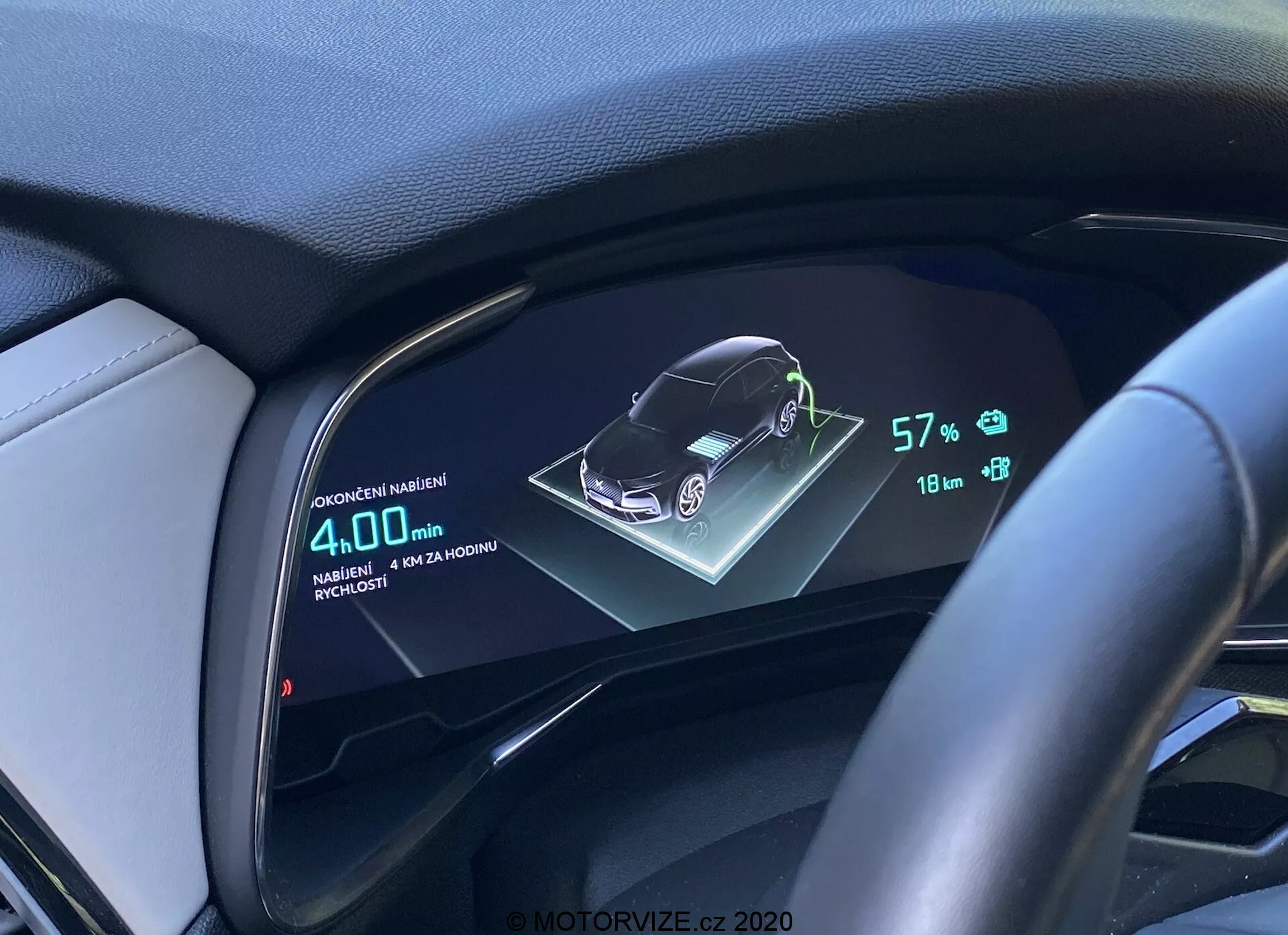 Digitálny displej palubnej dosky vozidla DS Automobiles DS-7 2018 (DS-7 Crossback) zobrazujúci 3D grafiku vozidla, stav batérie na úrovni 57%, dojazd 18 km a priemernú spotrebu paliva 4,0L/100km, z perspektívy vodiča s volantom a koženým obložením palubnej dosky.
