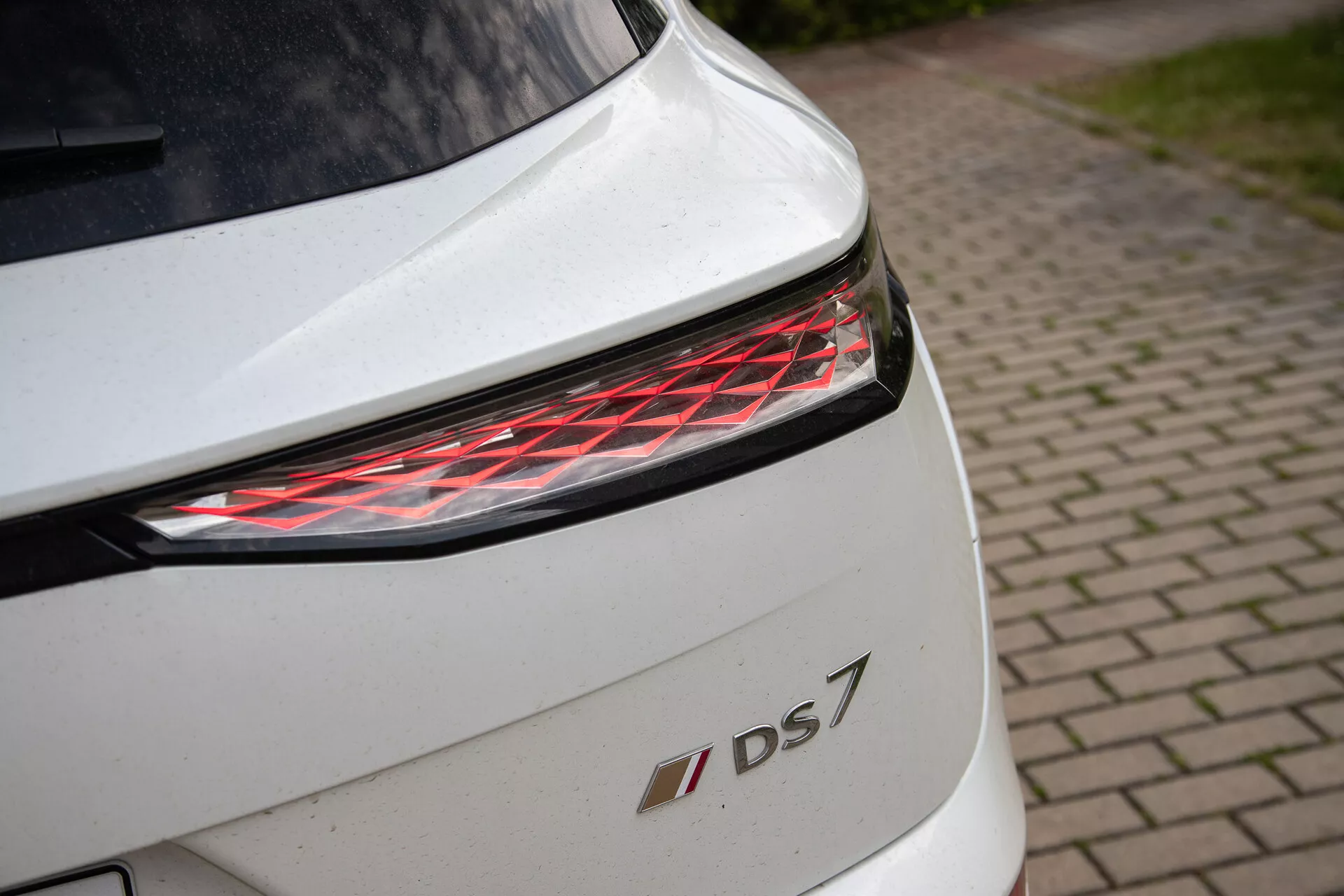 Detail zadnej časti bieleho DS 7 so súčasným LED zadným svetlom a emblémom modelu, zdôrazňujúci dizajnové detaily a prémiové prevedenie