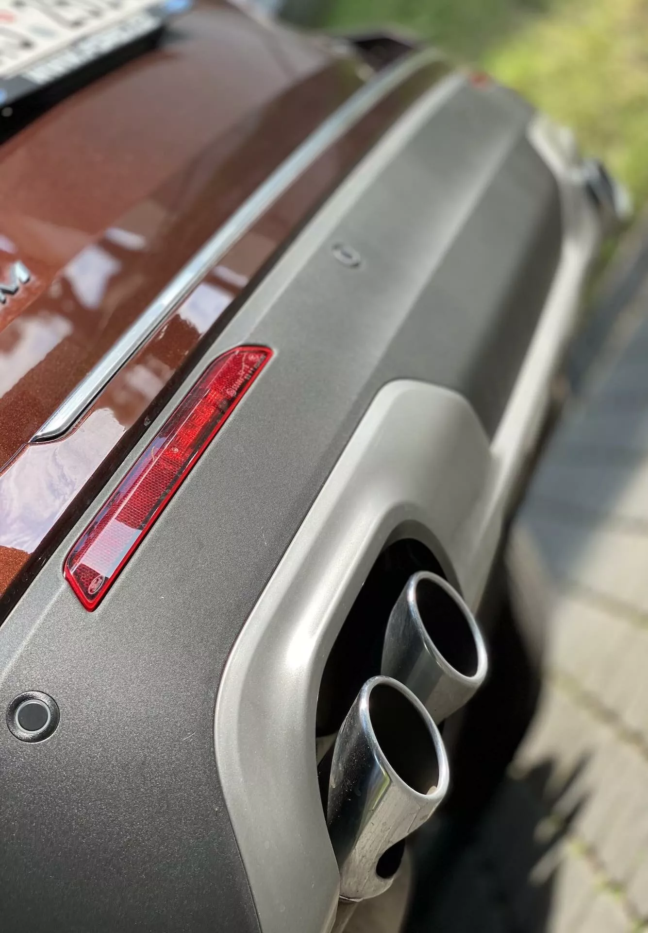 Detailný záber na zadnú časť Ford Explorer 2019, zobrazujúci metalickú farbu, zadný spojler, červené zadné svetlo a dvojité chrómované výfukové koncovky. Šikmý uhol z vyvýšenej pozície zdôrazňuje dobre udržiavaný povrch a moderné dizajnové prvky.