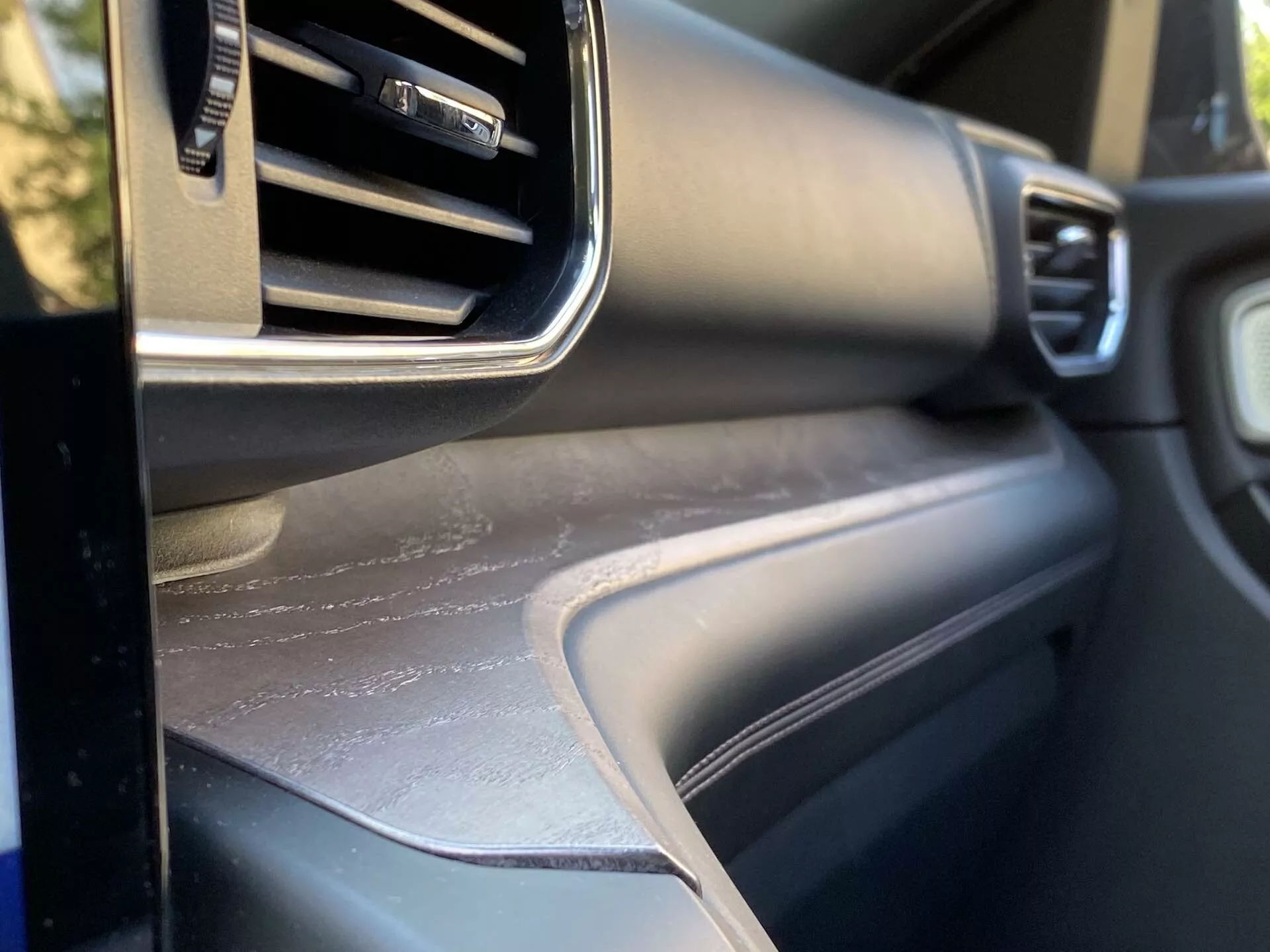 Zblízka pohľad na interiér auta Ford Explorer 2019, zameraný na palubnú dosku na strane spolujazdca s nastaviteľným ventilačným otvorom, kovovou výplňou, textúrovaným povrchom palubnej dosky a zodpovedajúcim dverovým panelom, ktorý predstavuje dizajn a kvalitu materiálov interiéru vozidla.
