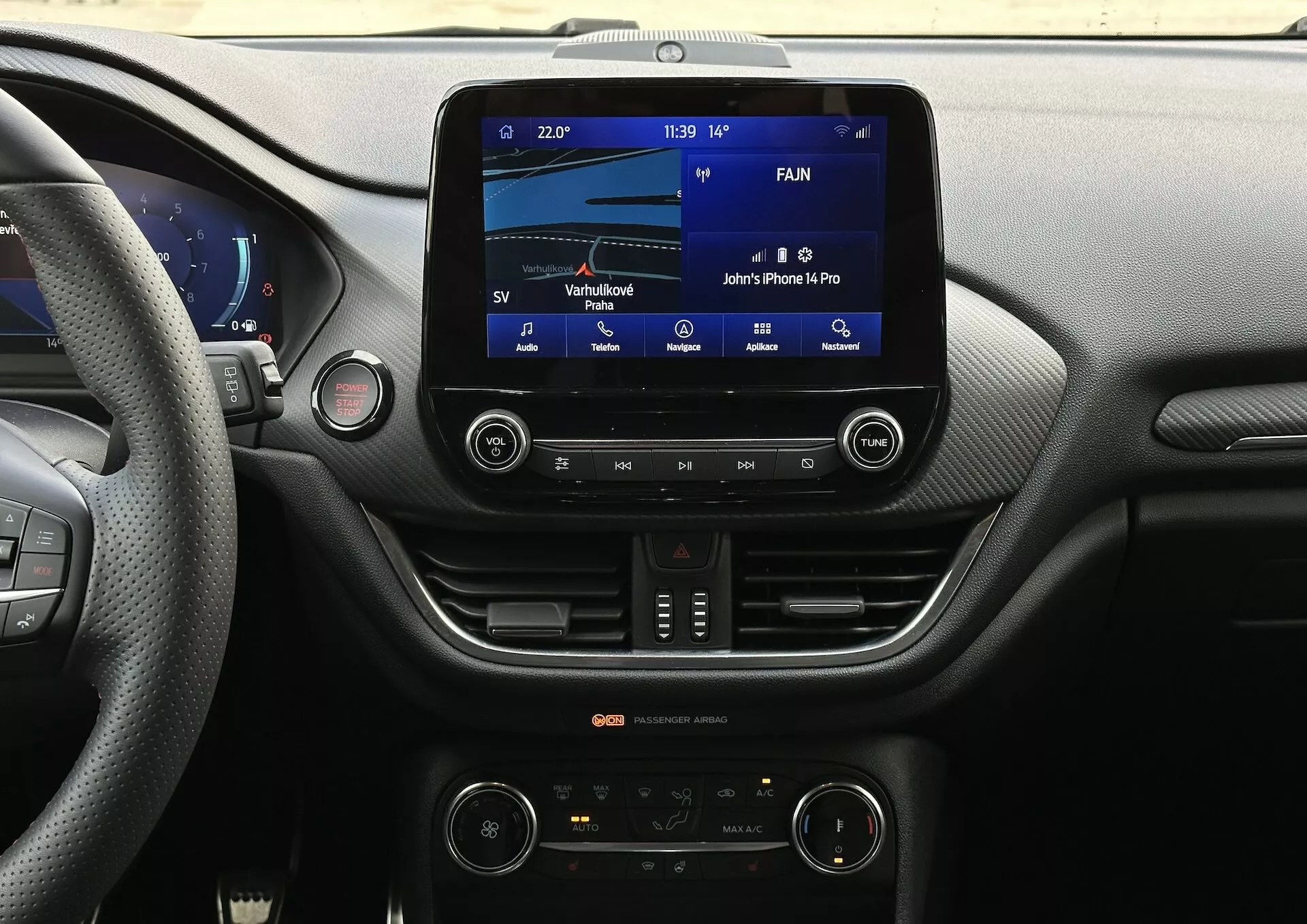 Pohľad na palubnú dosku interiéru Ford Fiesta 2022 z sedadla vodiča so zameraním na systém infotainment a funkcie stredovej konzoly vrátane dotykového displeja, pripojenia Bluetooth a dvojzónovej automatickej klímy