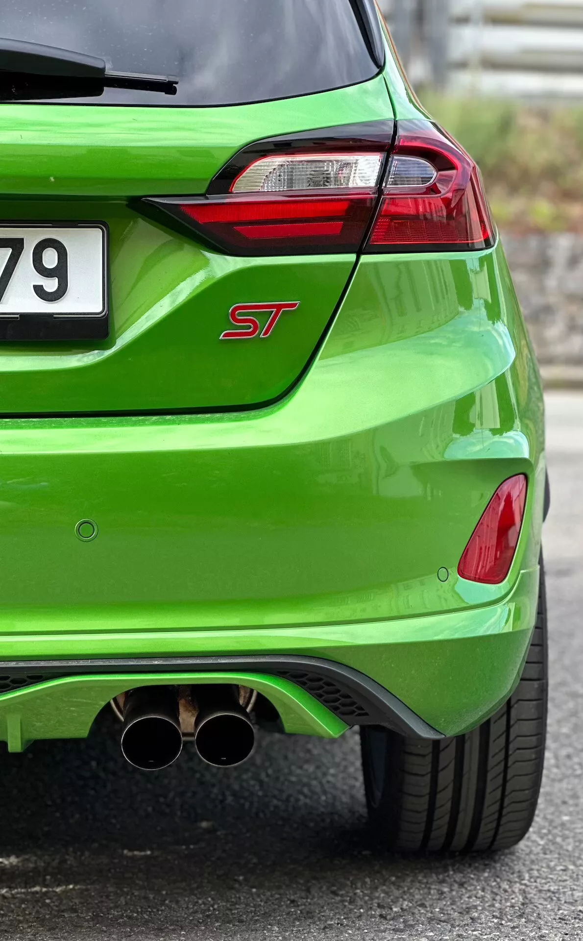 Detailný pohľad na zadnú časť Ford Fiesta ST 2022 v jasne zelenej metalíze, zdôrazňujúci LED zadné svetlá, dvojitú chromovanú výfukovú sústavu a aerodynamický zadný difúzor