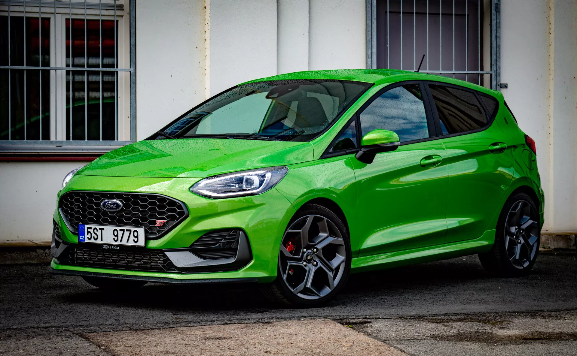 Svetlo zelený Ford Fiesta moderný model hatchback z roku 2022 zdôrazňujúci športovú postavu s výraznou prednou mriežkou a elegantnými LED svetlometmi, parkovaný šikmo pred budovou