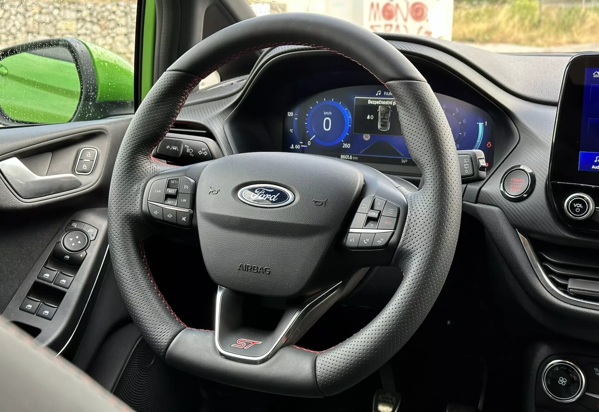 Interiér Ford Fiesta 2022 zameraný na kožený volant s tromi ramenami s multifunkčnými ovládacími prvkami a digitálnym palubným panelom z perspektívy sedadla vodiča